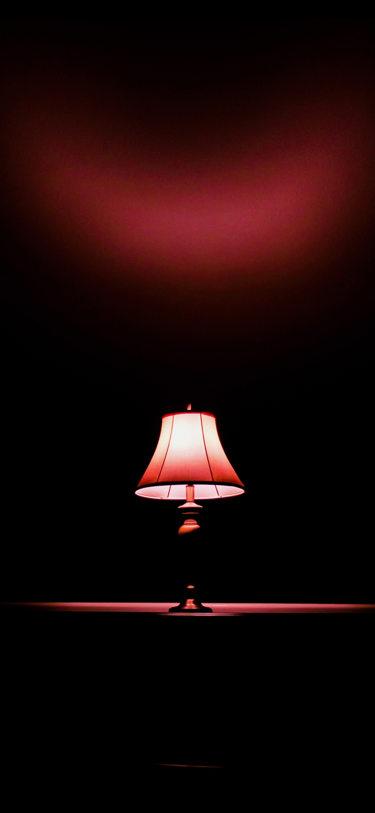 A lamp is turned on in a dark room. - Light red