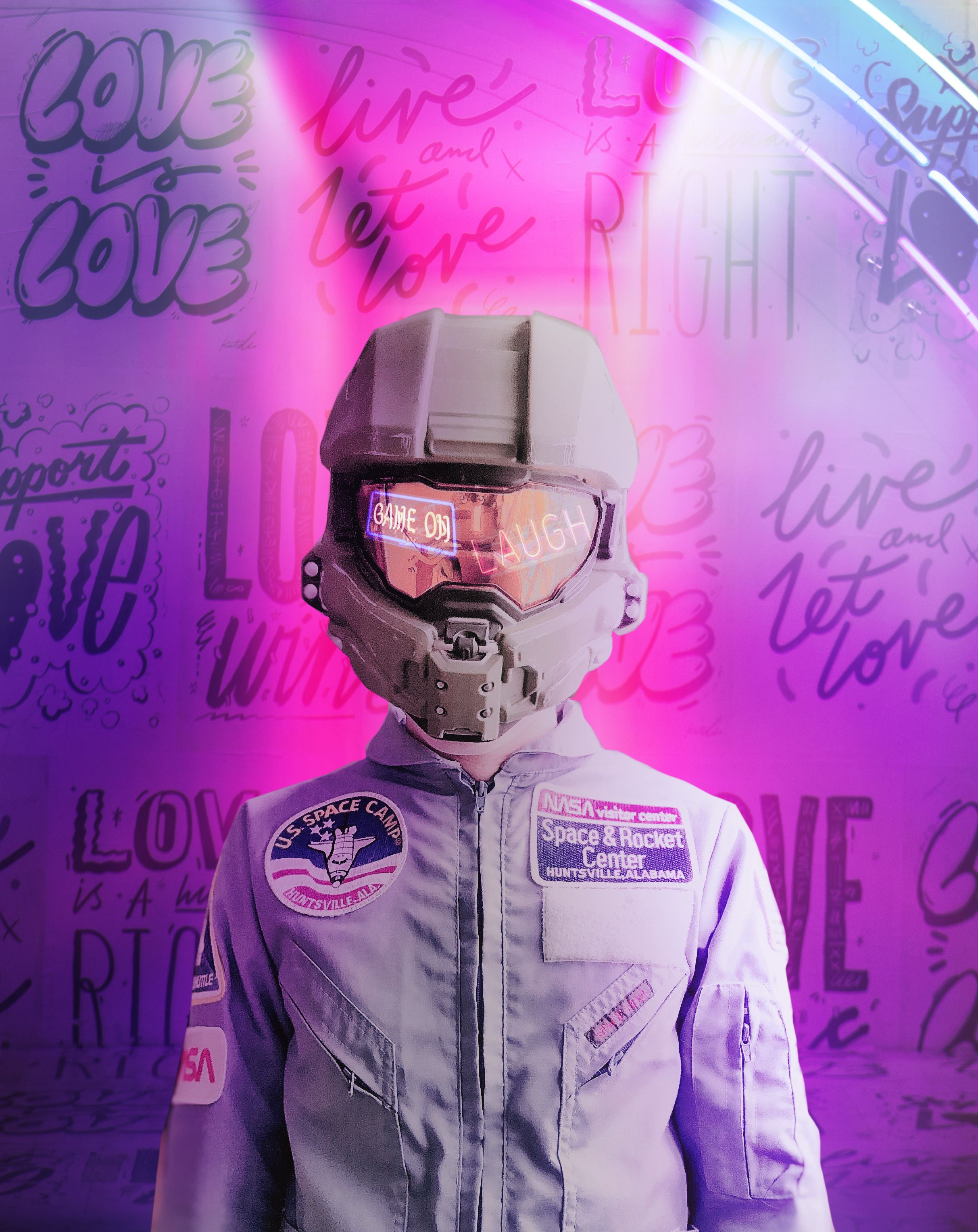 A person in an astronaut suit standing next to some neon lights - NASA