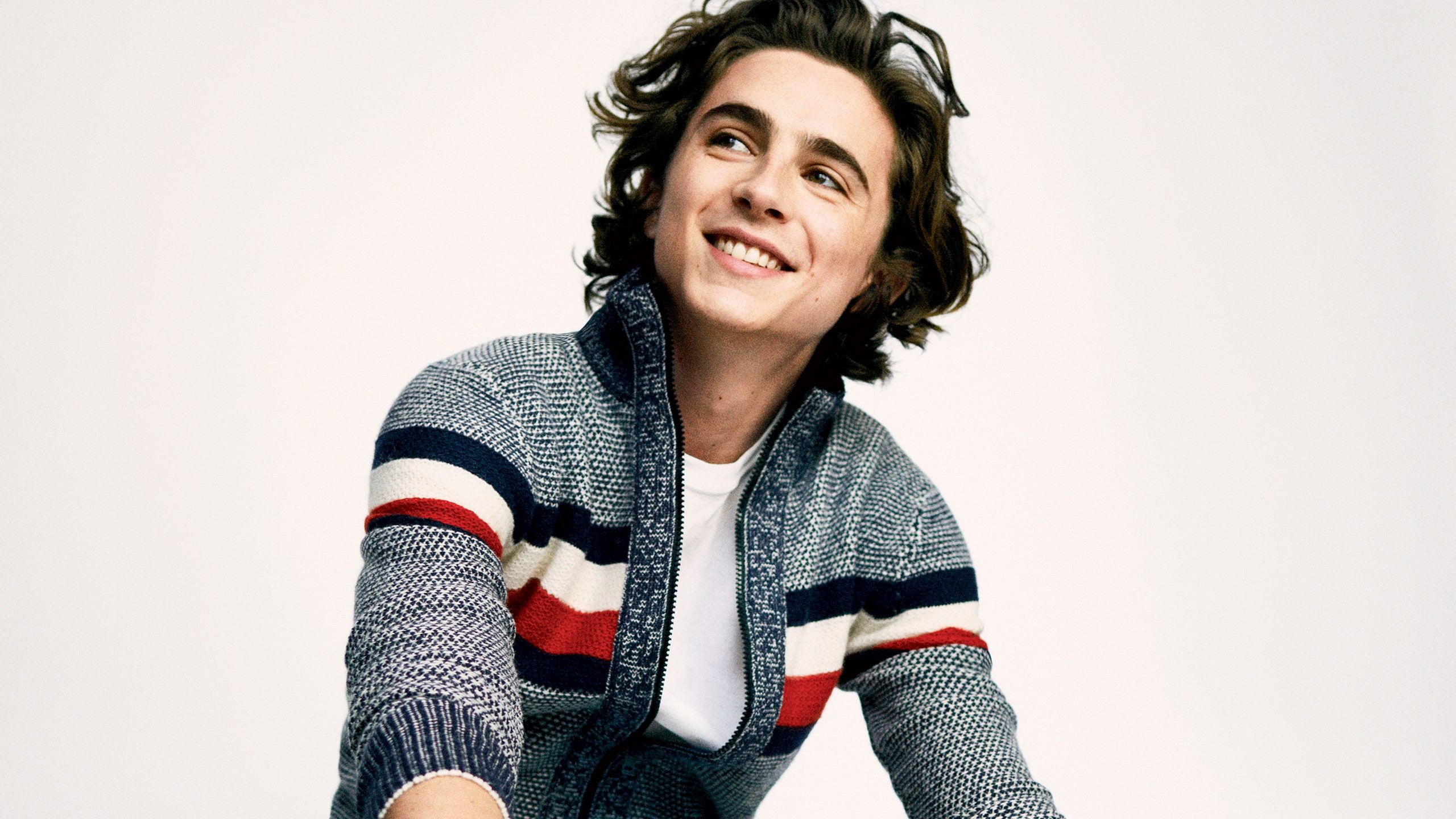 Timothe Chalamet sitting on the ground wearing a striped sweater - Timothee Chalamet