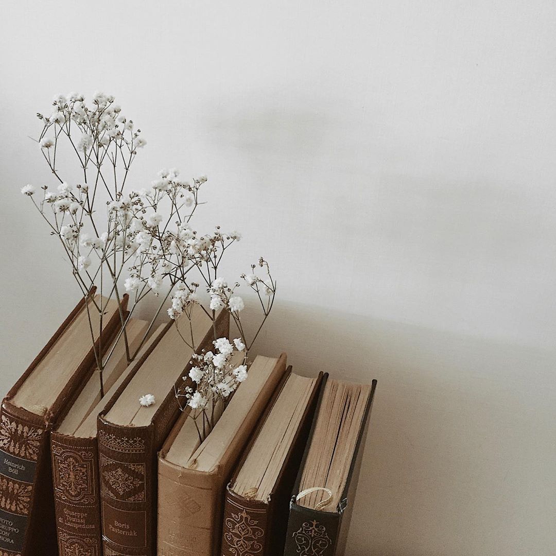 A stack of books with flowers in them. - Light academia