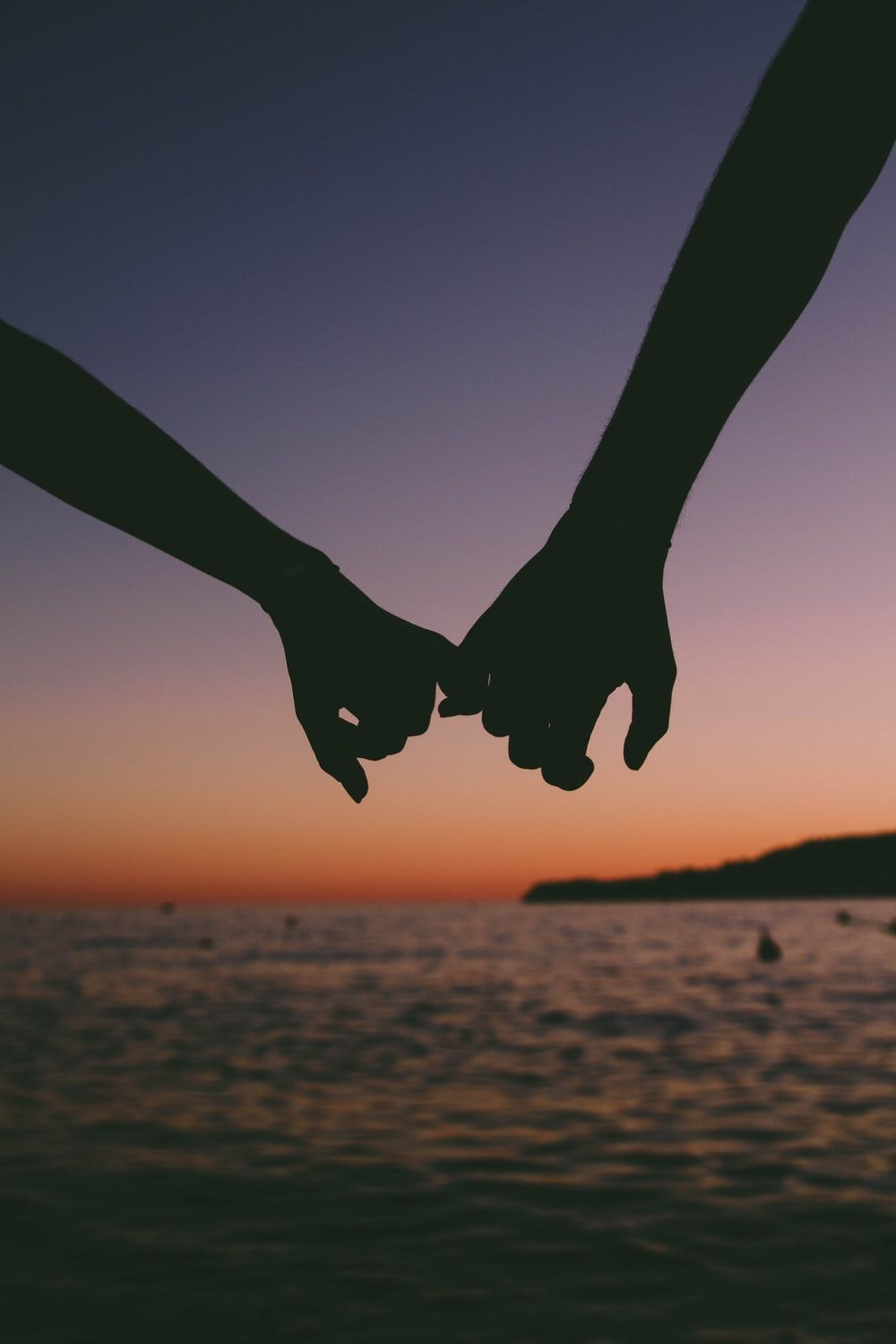 A couple holding hands over the ocean - 