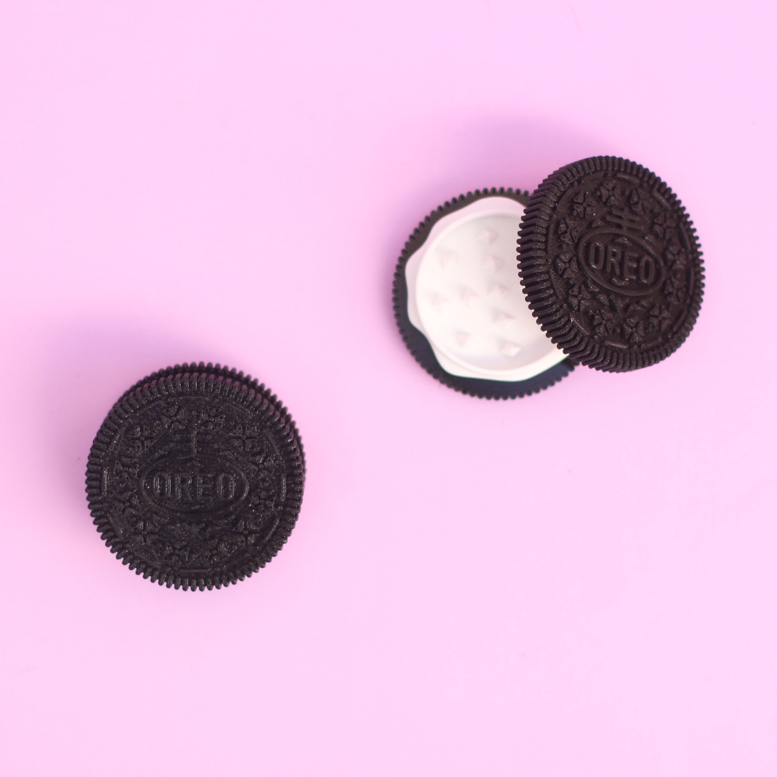 Two oreo cookies on a pink background. - Oreo