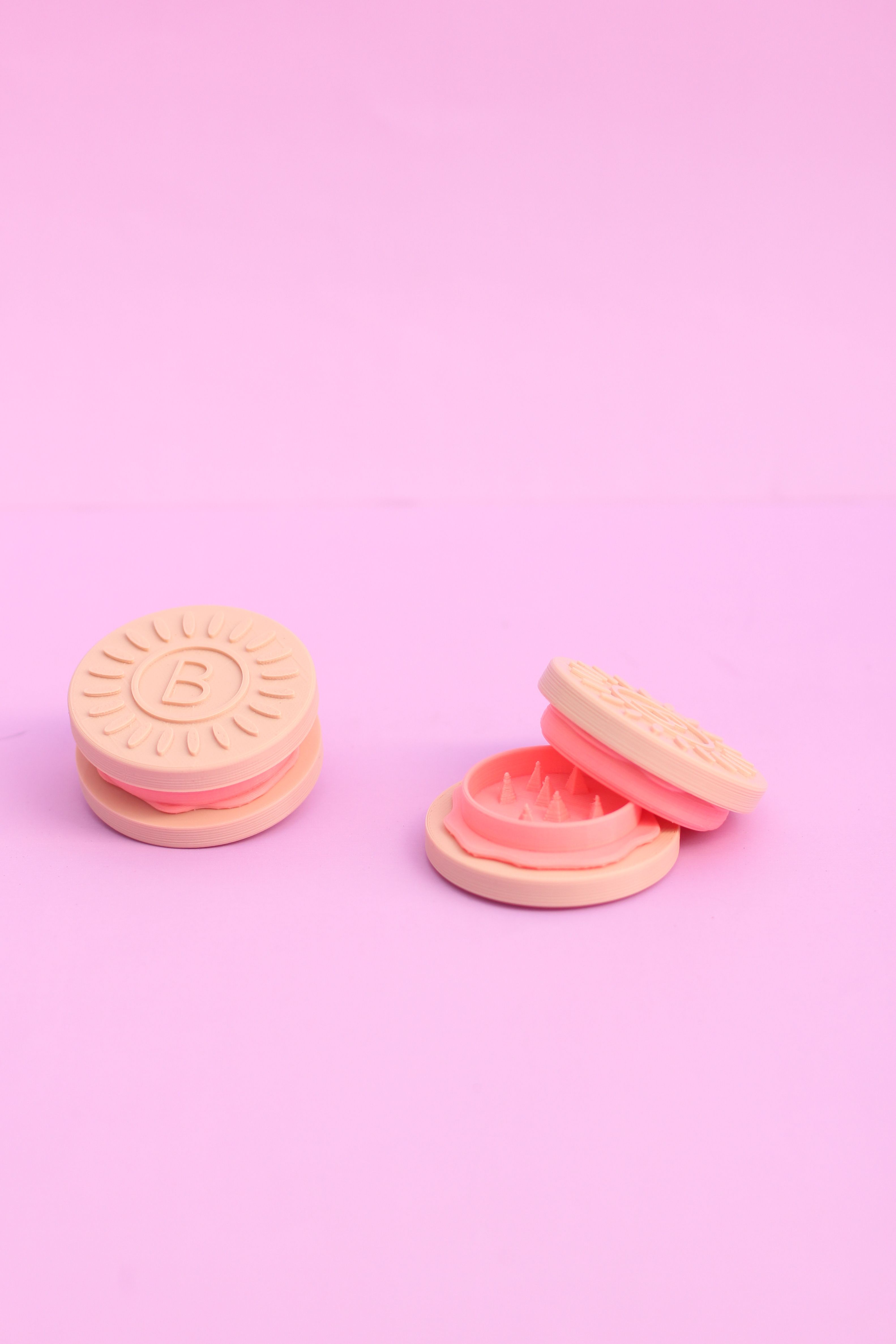 Two halves of a pink and white cookie on a pink background - Oreo