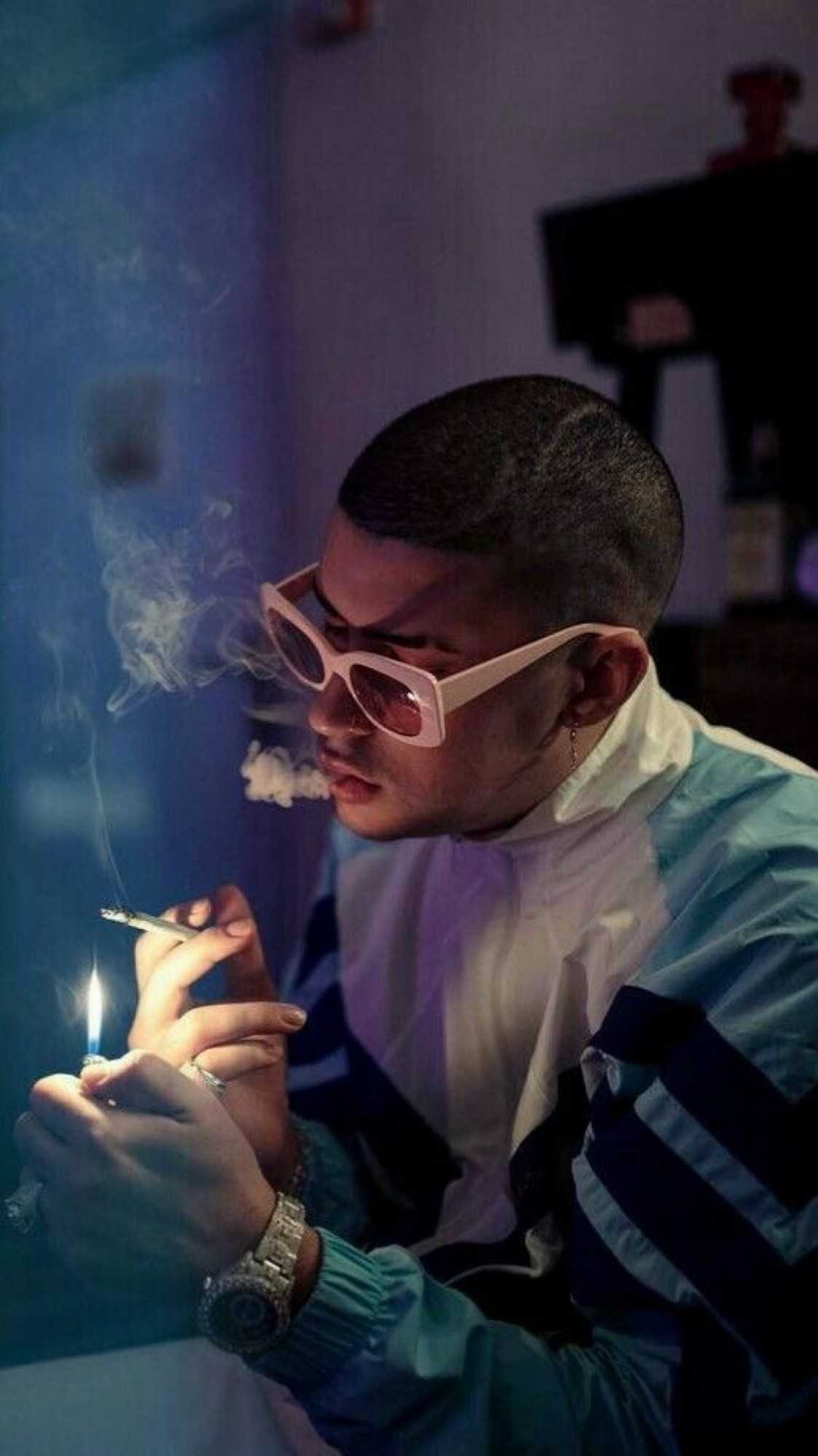 A man in sunglasses smoking while sitting at the table - Bad Bunny