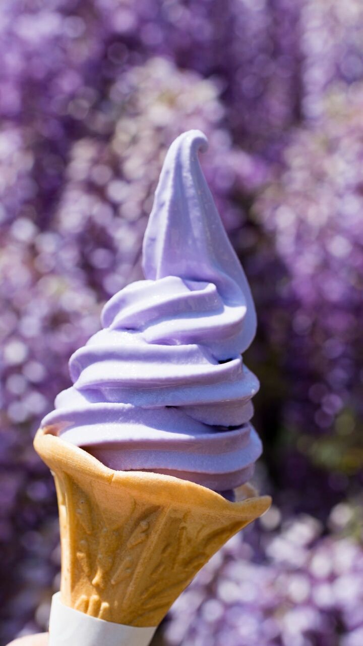 A close up of a cone with purple ice cream on it - Ice cream