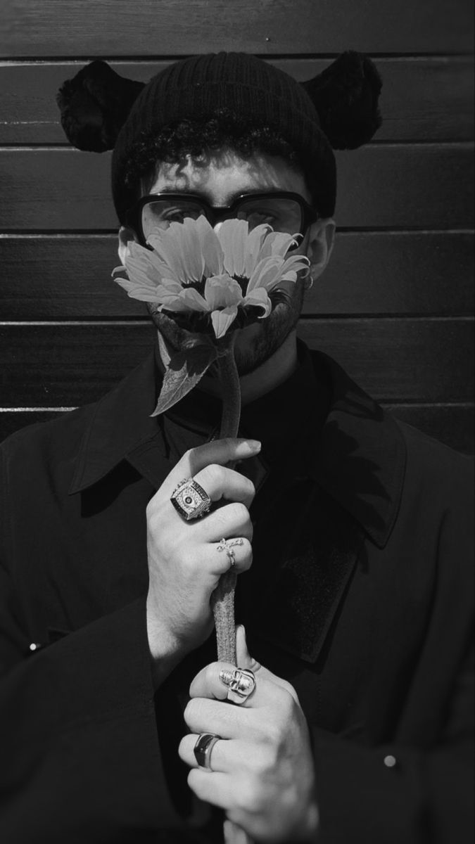 A man with a flower covering his face. - Bad Bunny