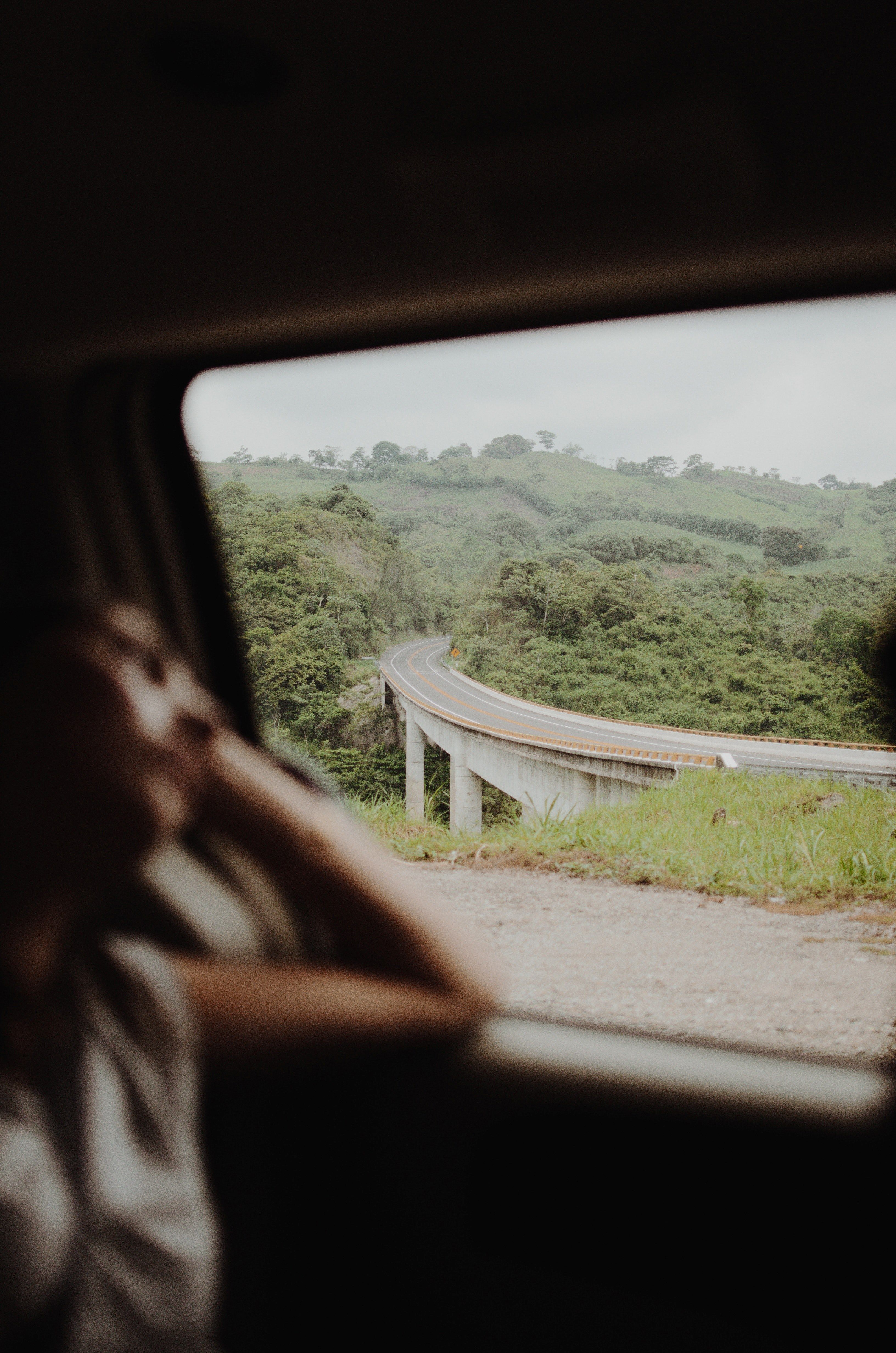 A woman looking out the window of a car at a winding road - Blurry