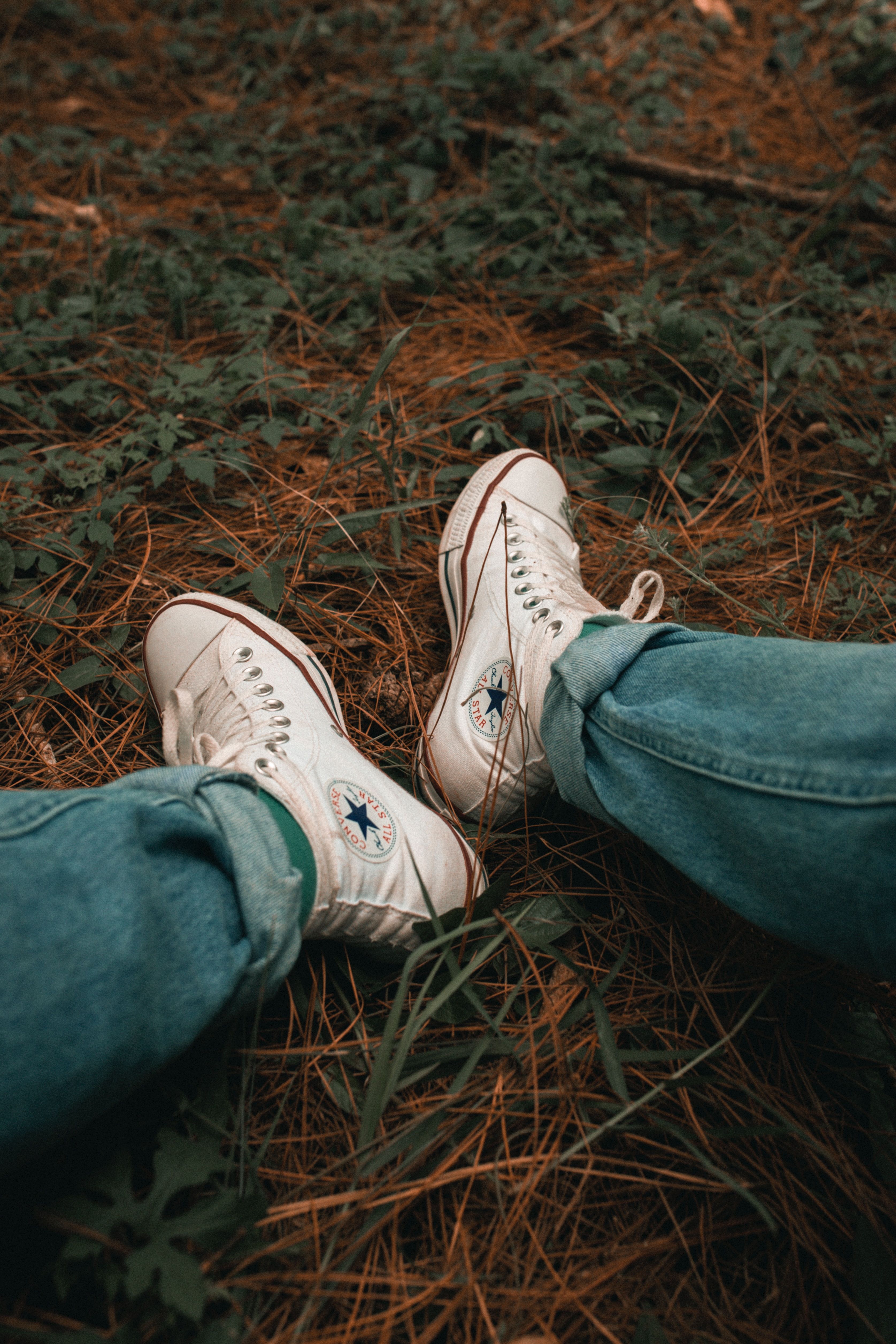 A person sitting on the ground with their shoes off - Shoes