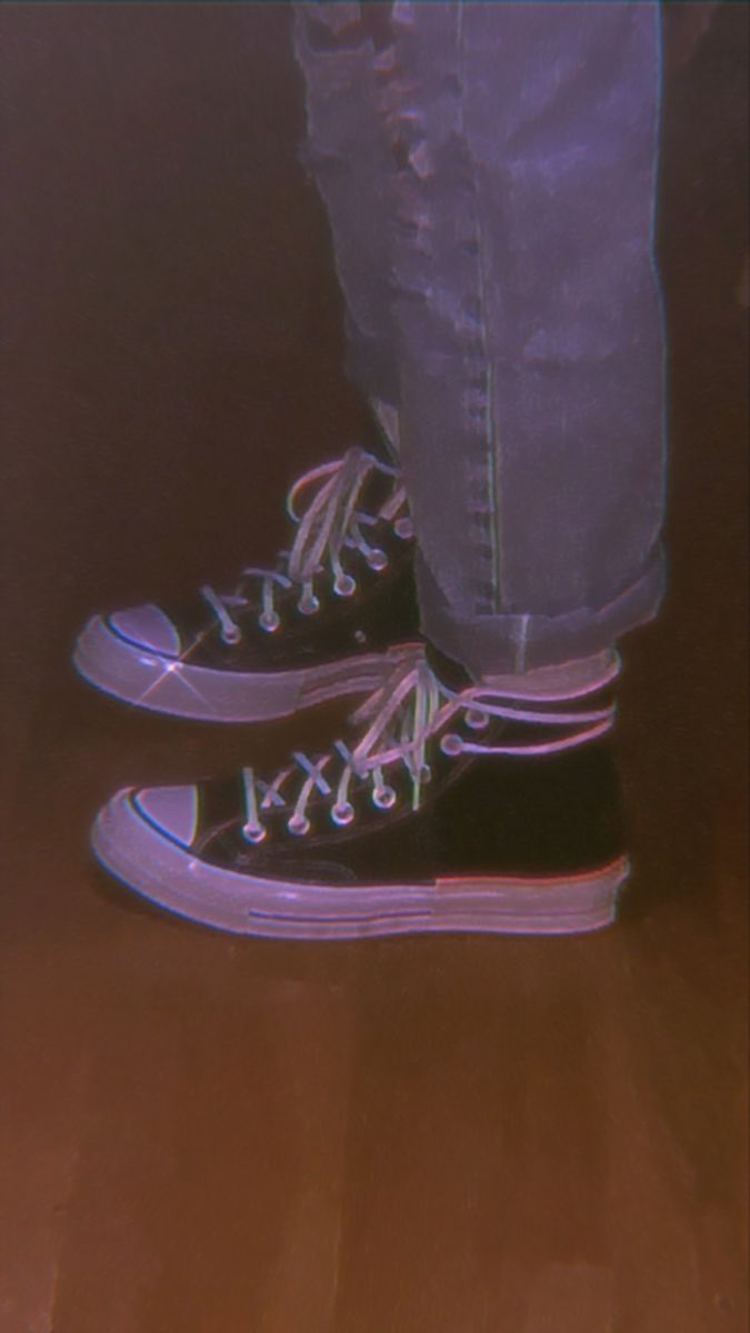 A person standing on the floor wearing sneakers - Shoes