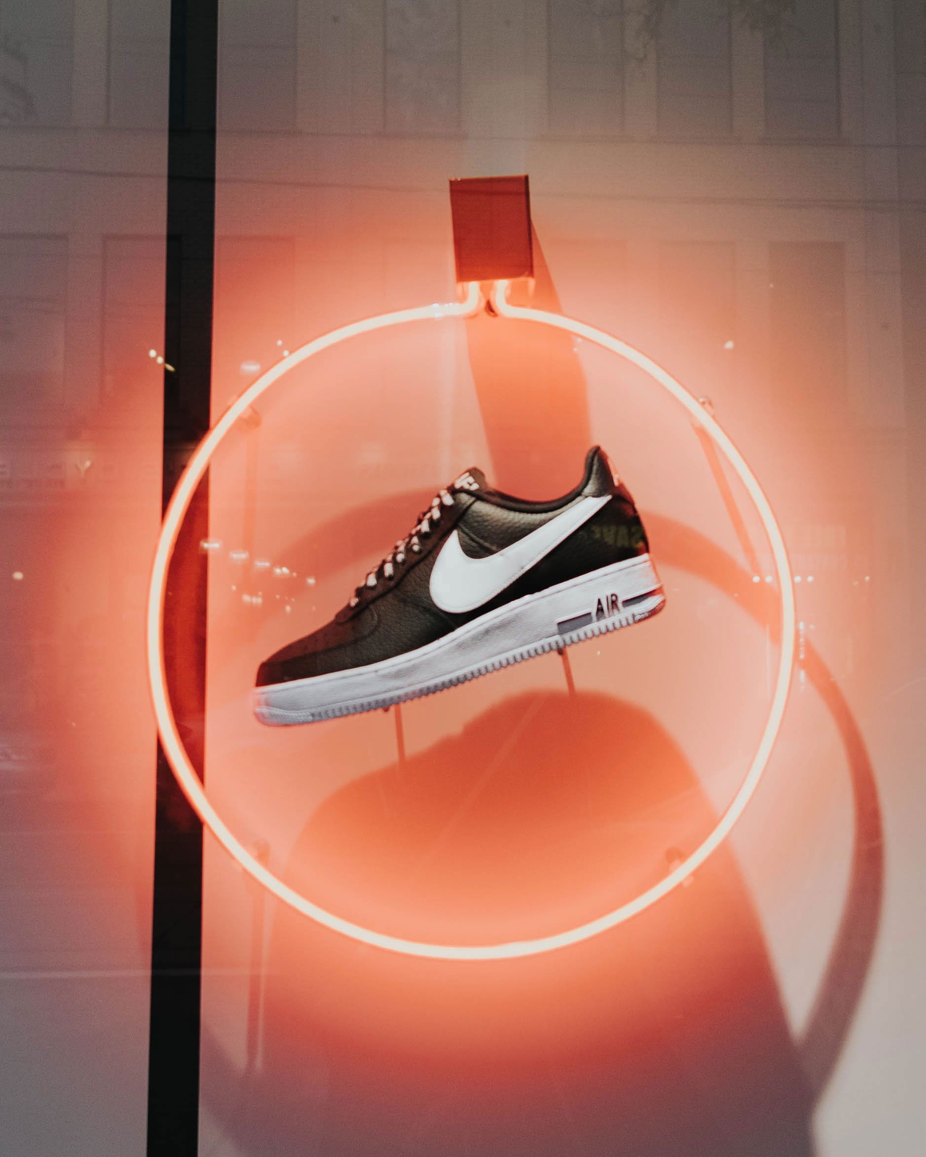 A pair of black and white Nike sneakers on display in a store window. - Neon orange, shoes, Nike