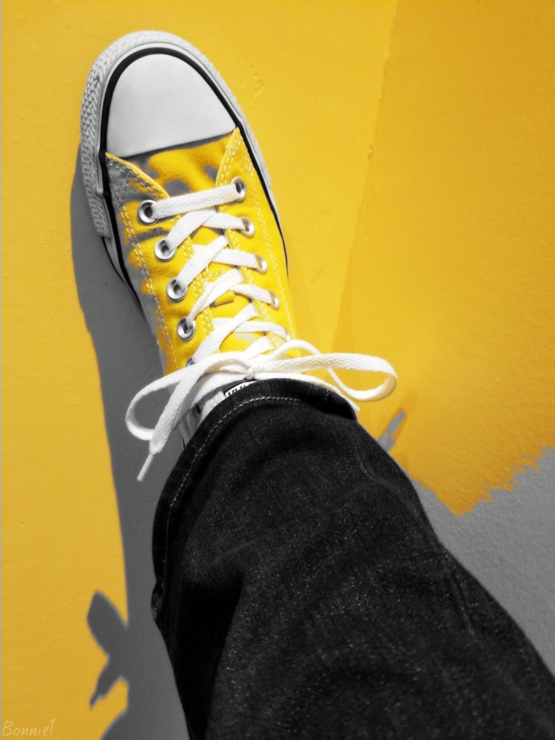 A person wearing yellow sneakers standing on top of something - Shoes
