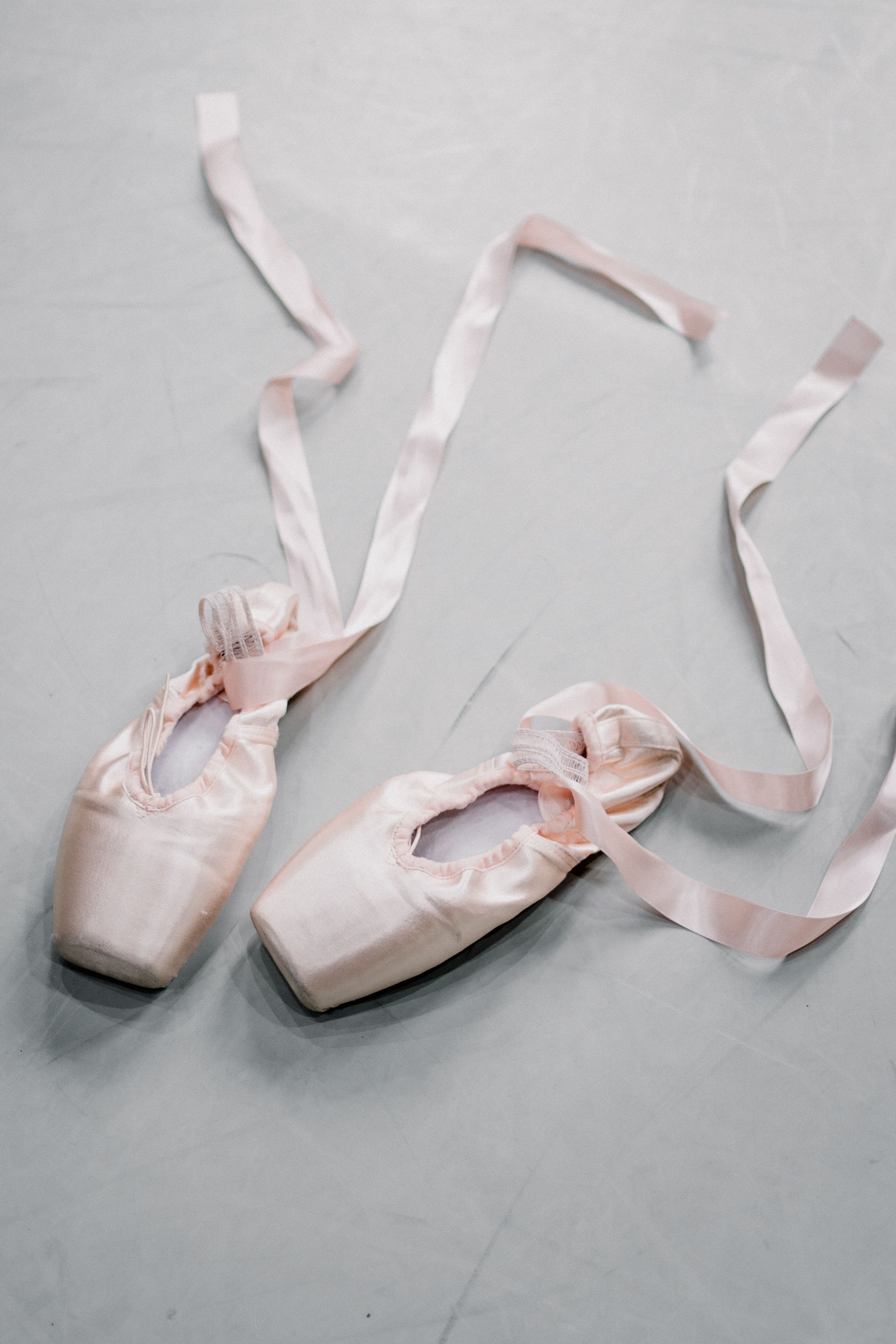 A pair of pink ballet shoes with ribbons on the floor - Shoes, ballet