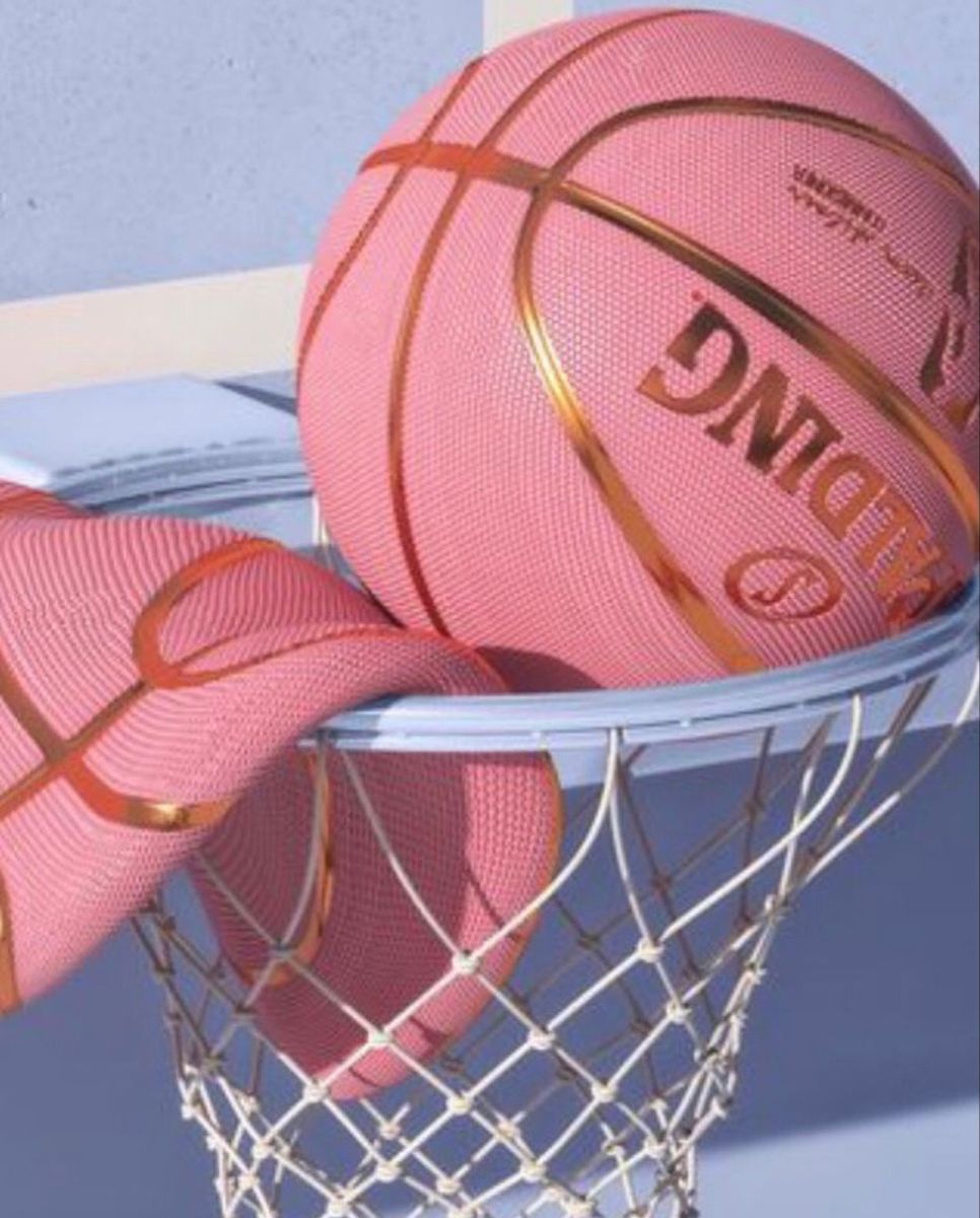A pink basketball sitting in a white basketball hoop - Basketball