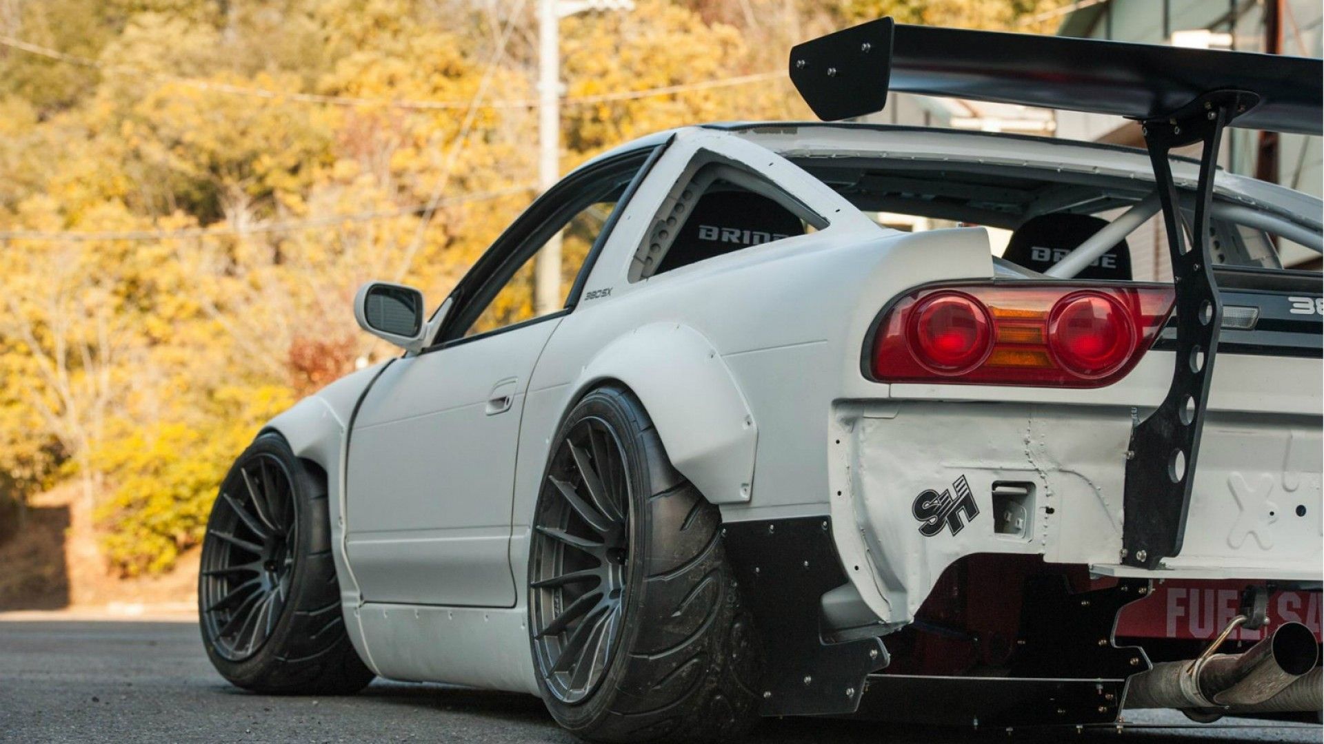 The rear end of a white nissan 240sx with a massive wing - JDM