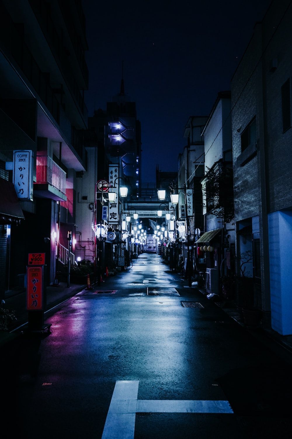 A street with buildings on either side at night - Tokyo