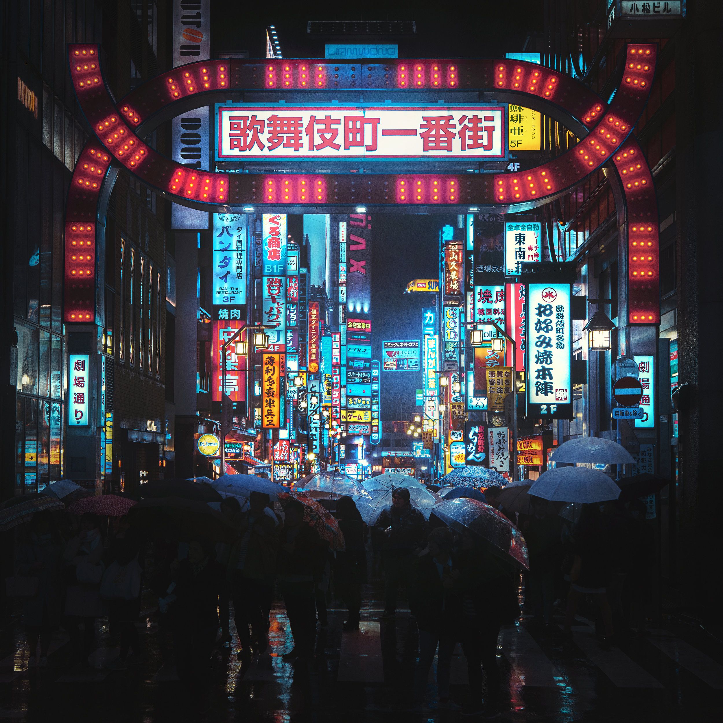 A crowded street at night with people holding umbrellas and neon signs - Tokyo