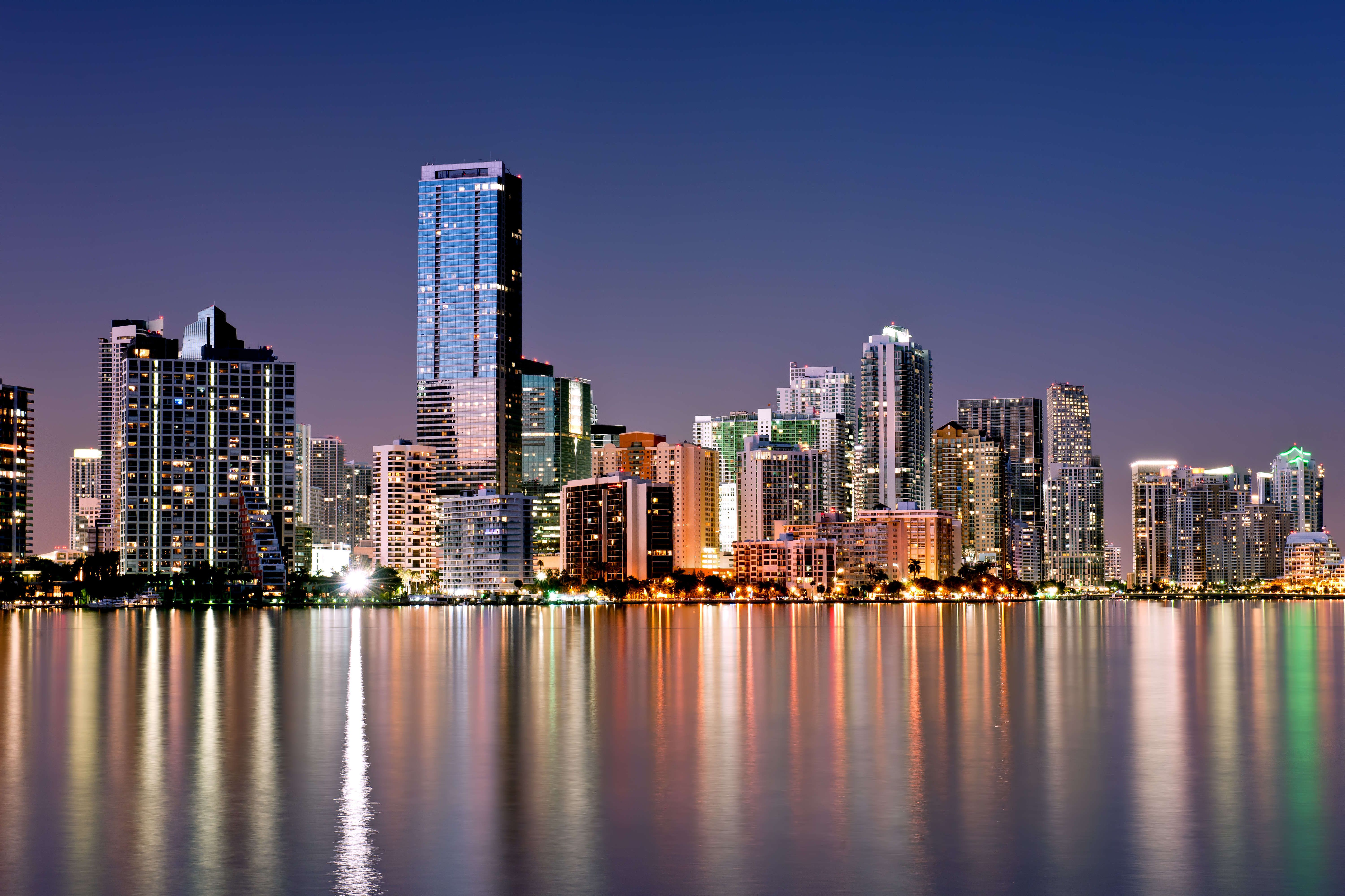 A city skyline at night with water in the foreground - Miami