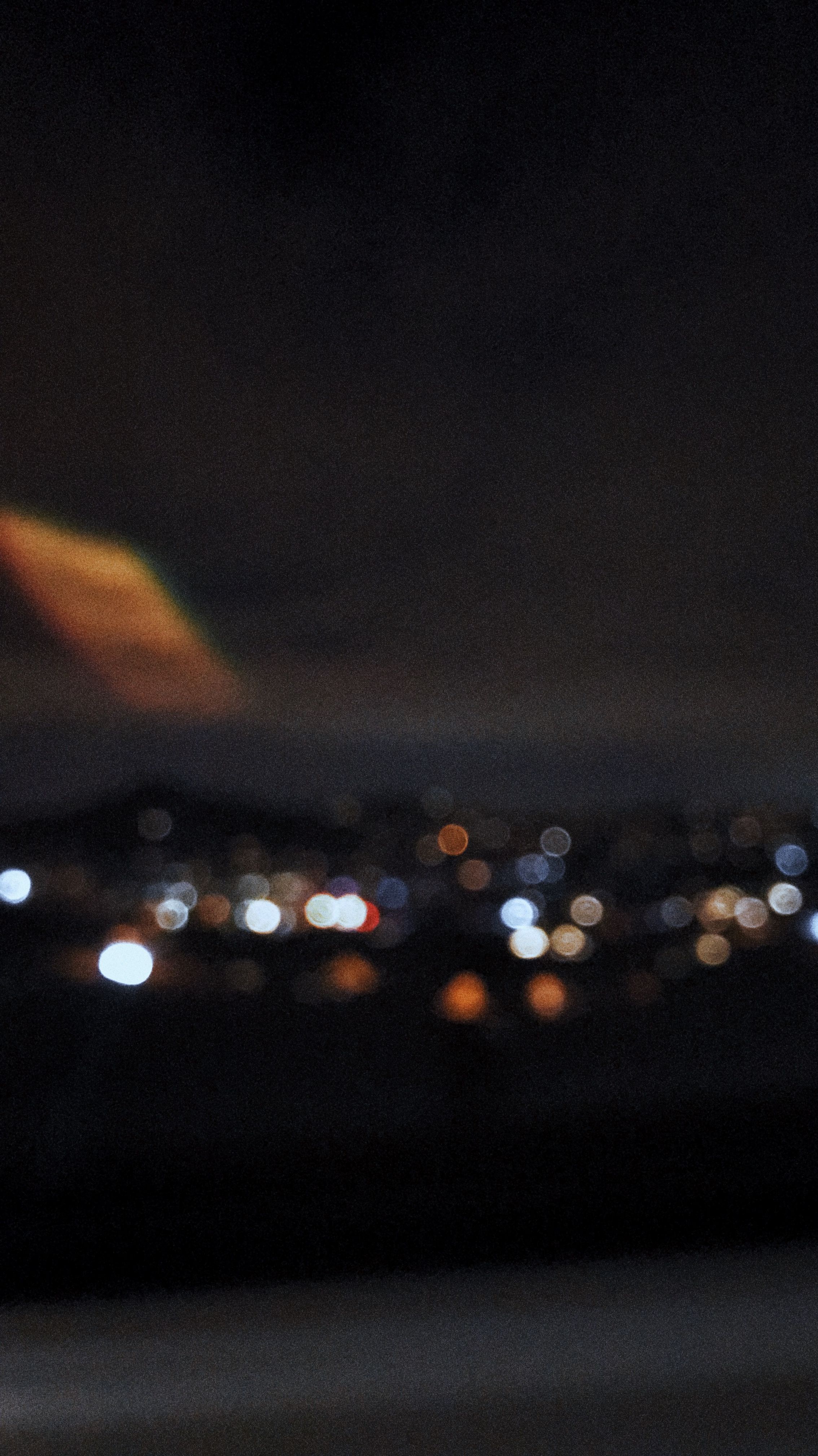 A blurry image of a city at night with lights shining in the distance. - Blurry
