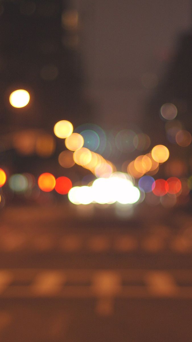 A blurry photo of a city street at night with street lights and car lights - Blurry