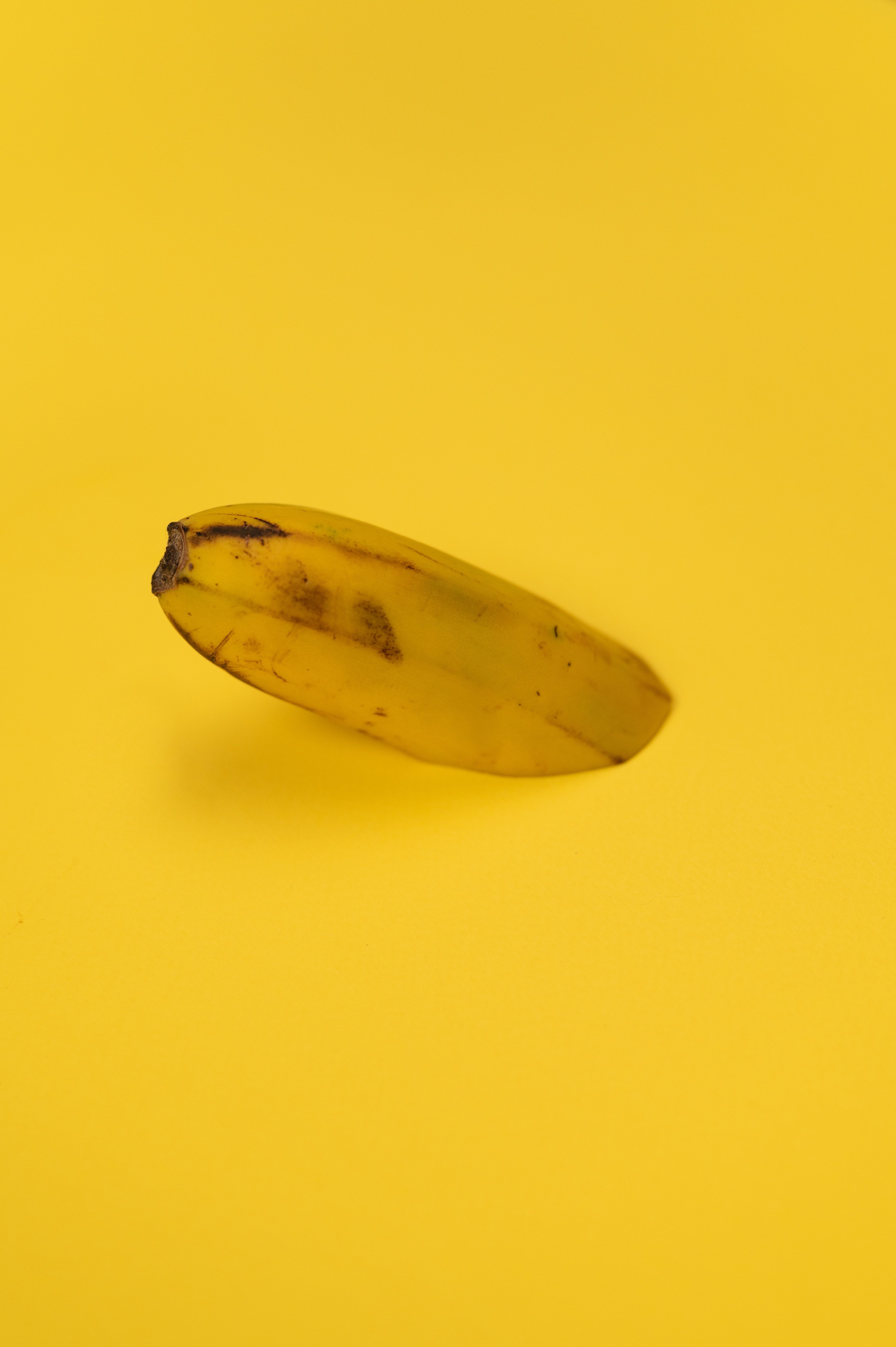 A single banana on a yellow background. - Banana