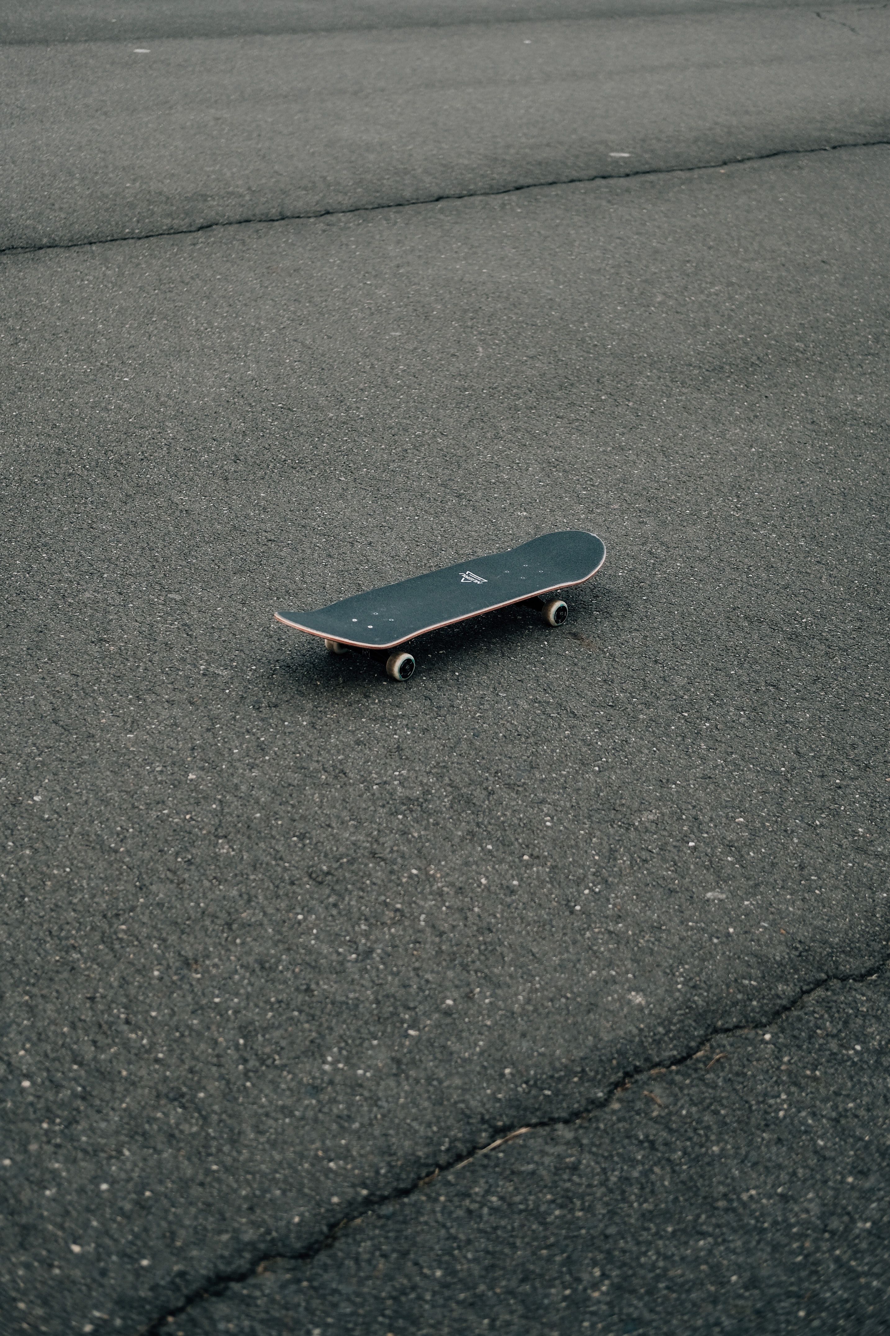 A skateboard sitting on the ground in an empty parking lot - Skate, skater