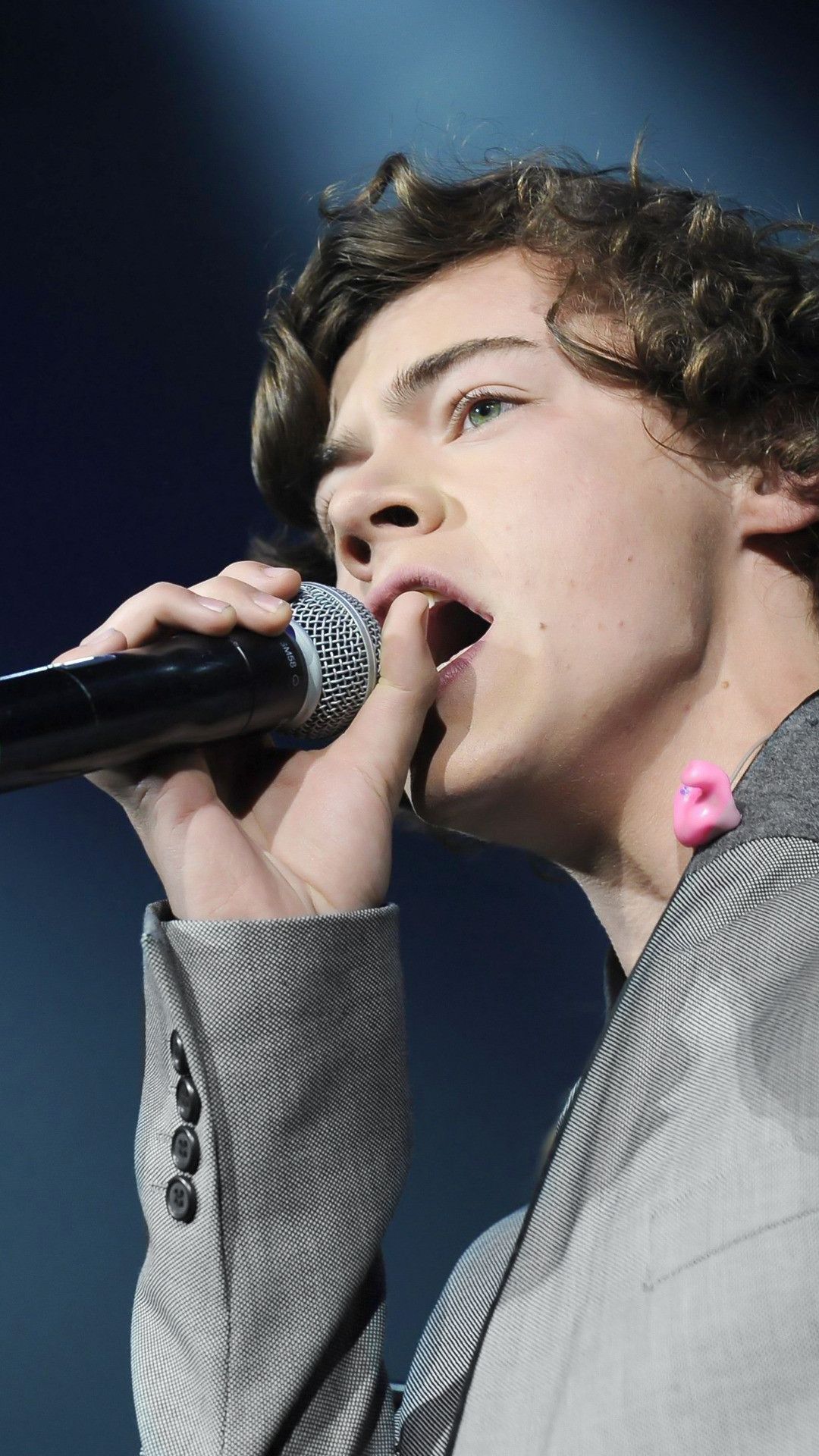 A young man singing into microphone - Harry Styles