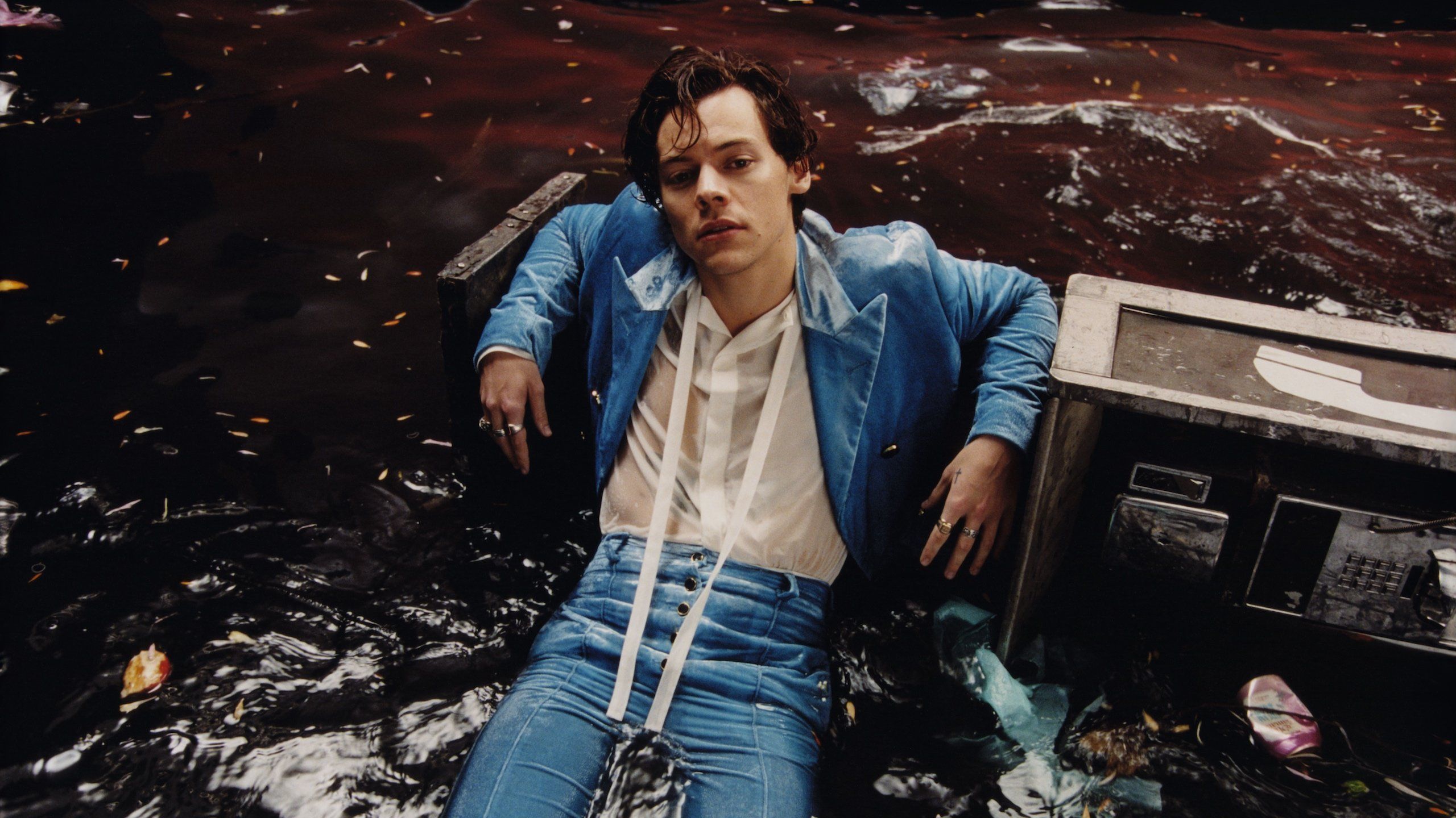 A man laying in the water with his arms crossed - Harry Styles