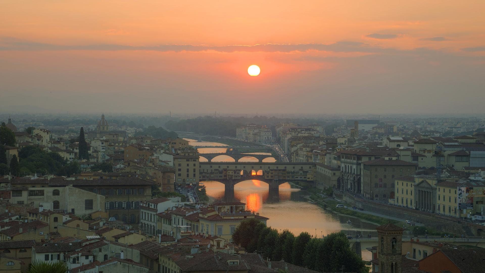 The sun sets over Florence, Italy, with the Ponte Vecchio bridge in the foreground. - Italy