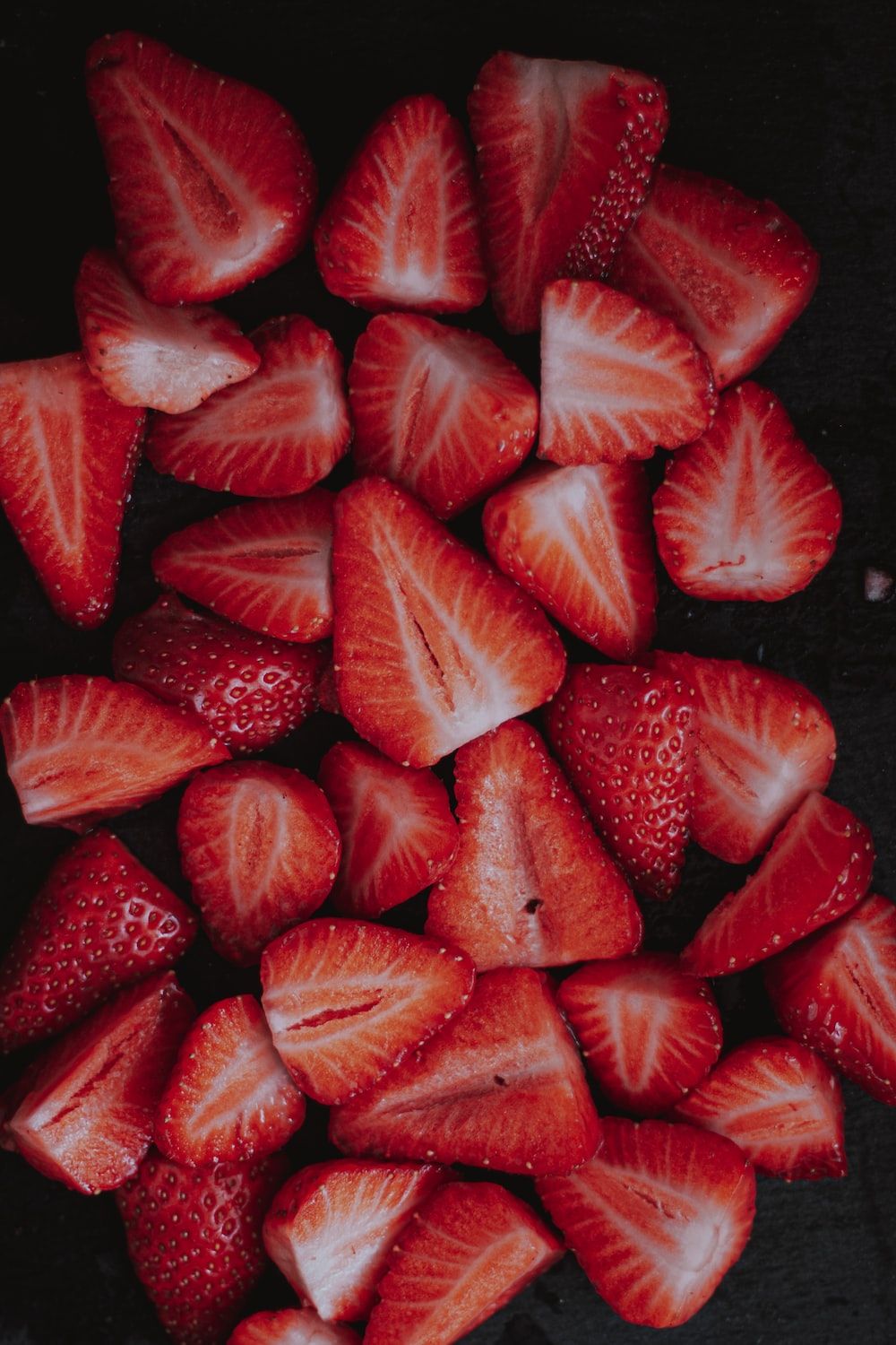 sliced strawberries on black surface photo