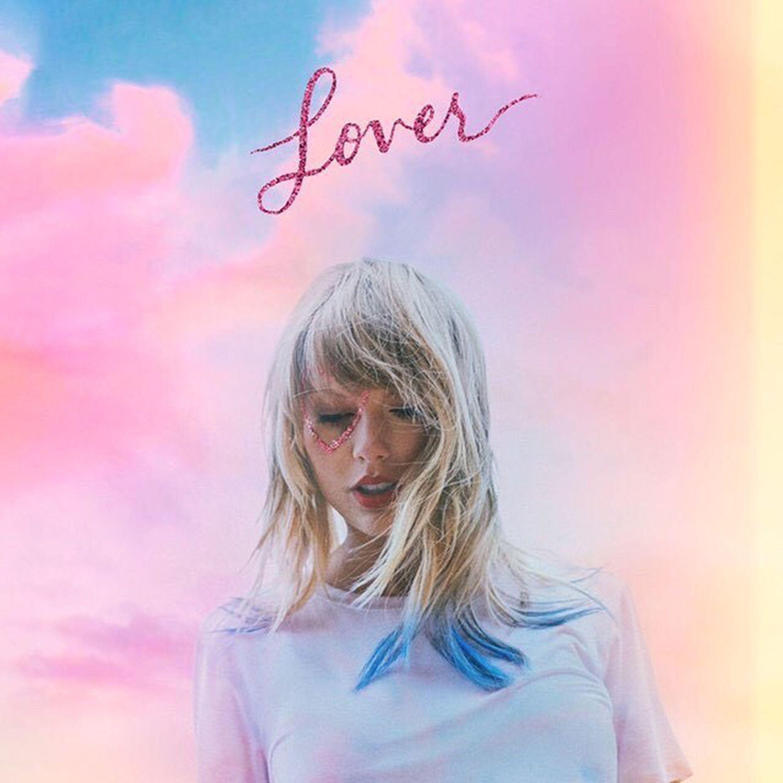 Taylor Swift's Lover album cover, with the singer in a white t-shirt in front of a pink and blue sky. - Taylor Swift