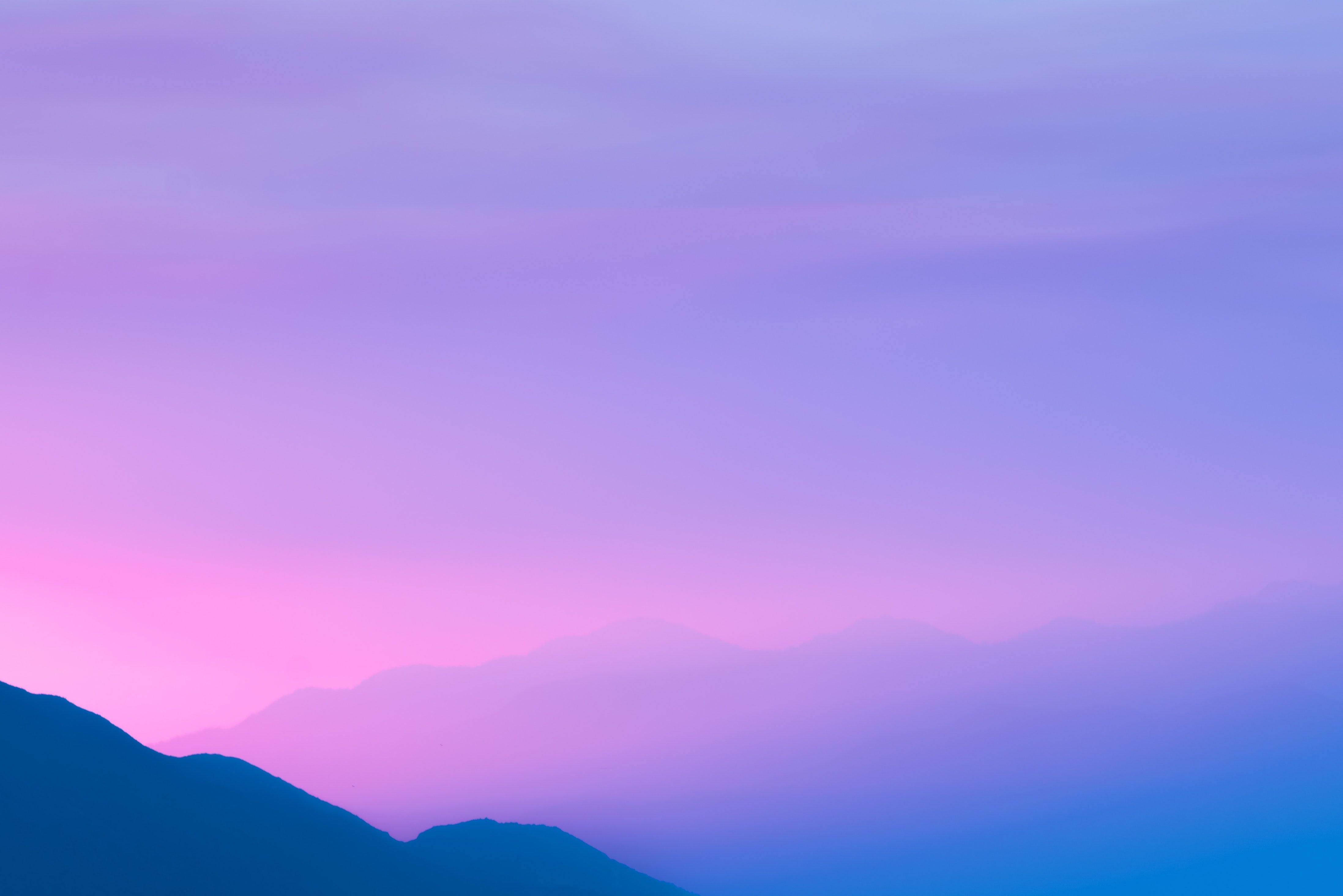 A mountain with pink and purple clouds in the sky - Light purple