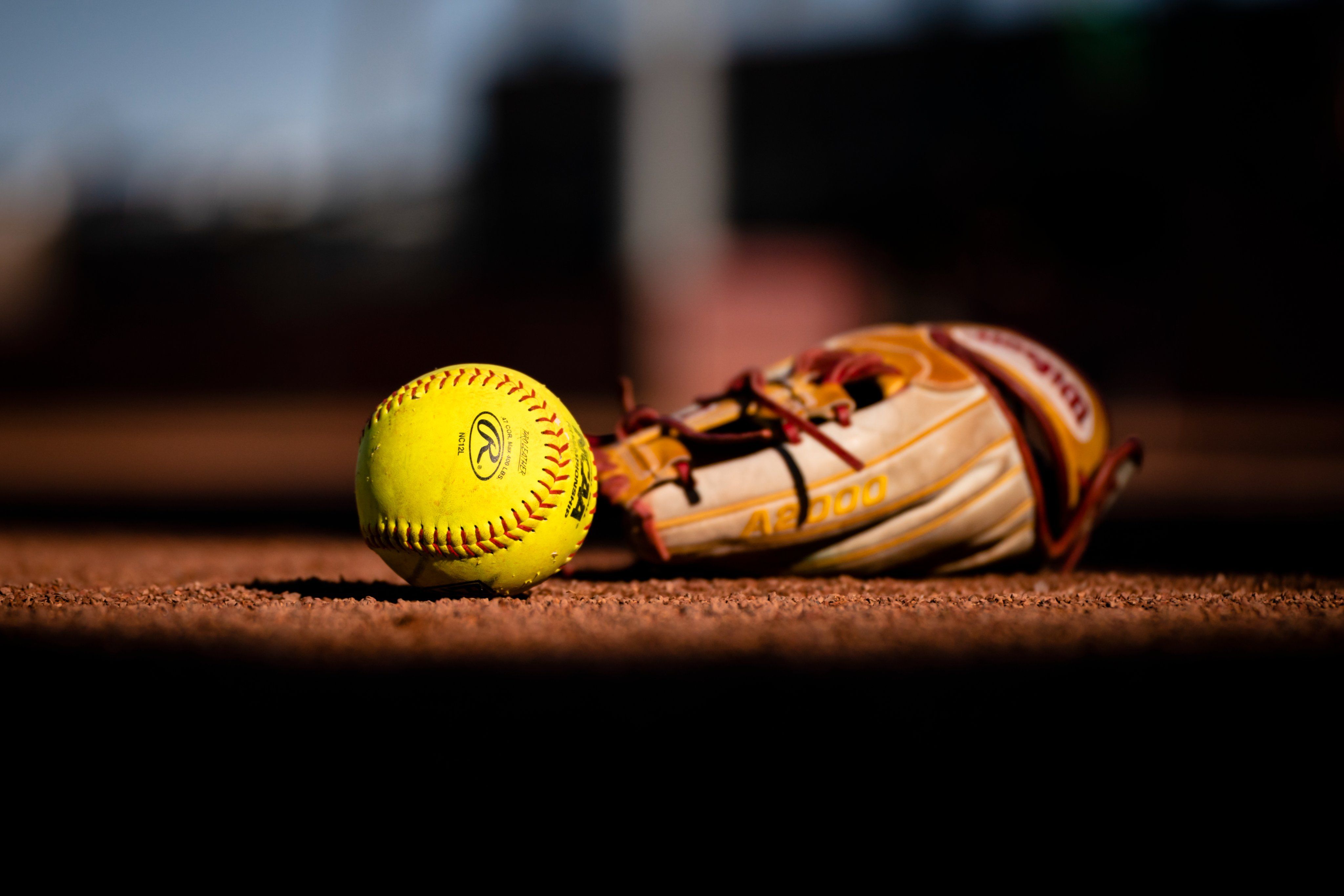 A softball and glove on the field - Softball