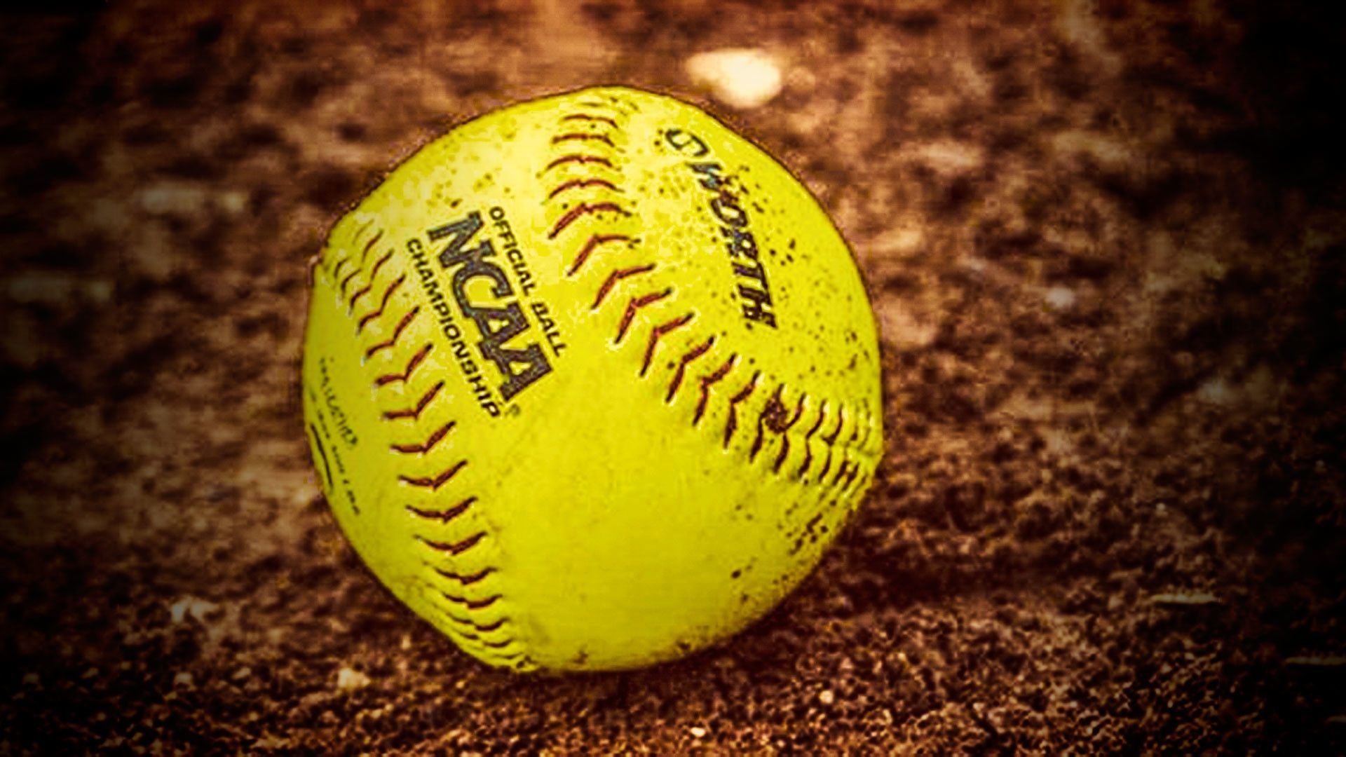 A yellow softball sits on the dirt. - Softball