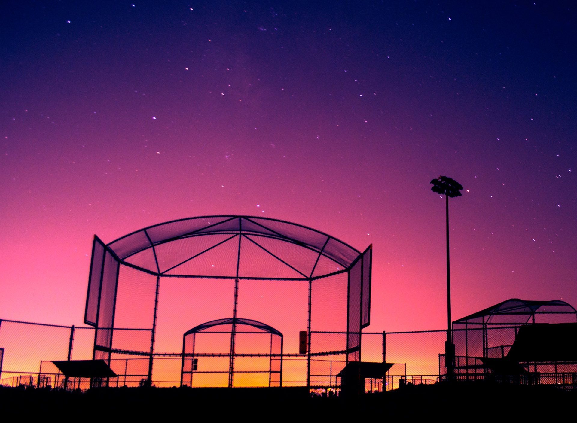 A baseball field under a starry sky at sunset. - Softball