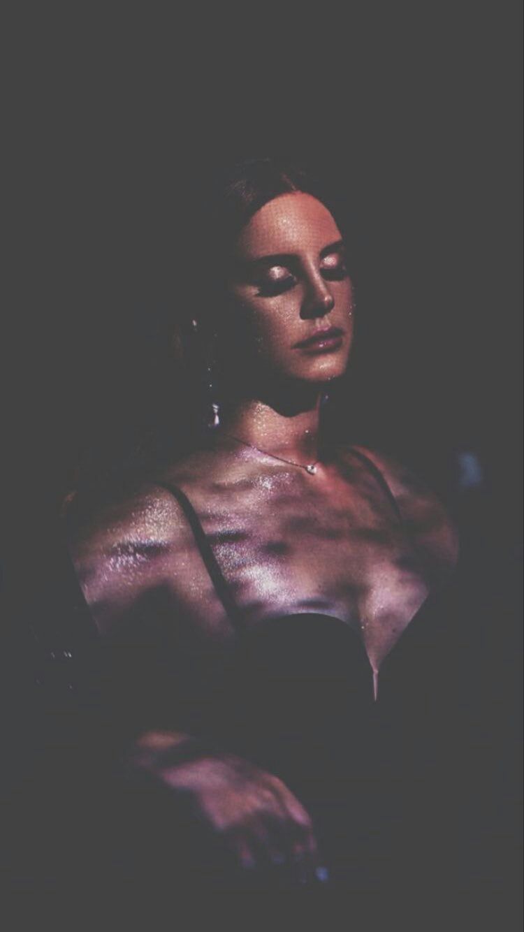 A woman with her eyes closed and her arms in front of her chest. - Lana Del Rey