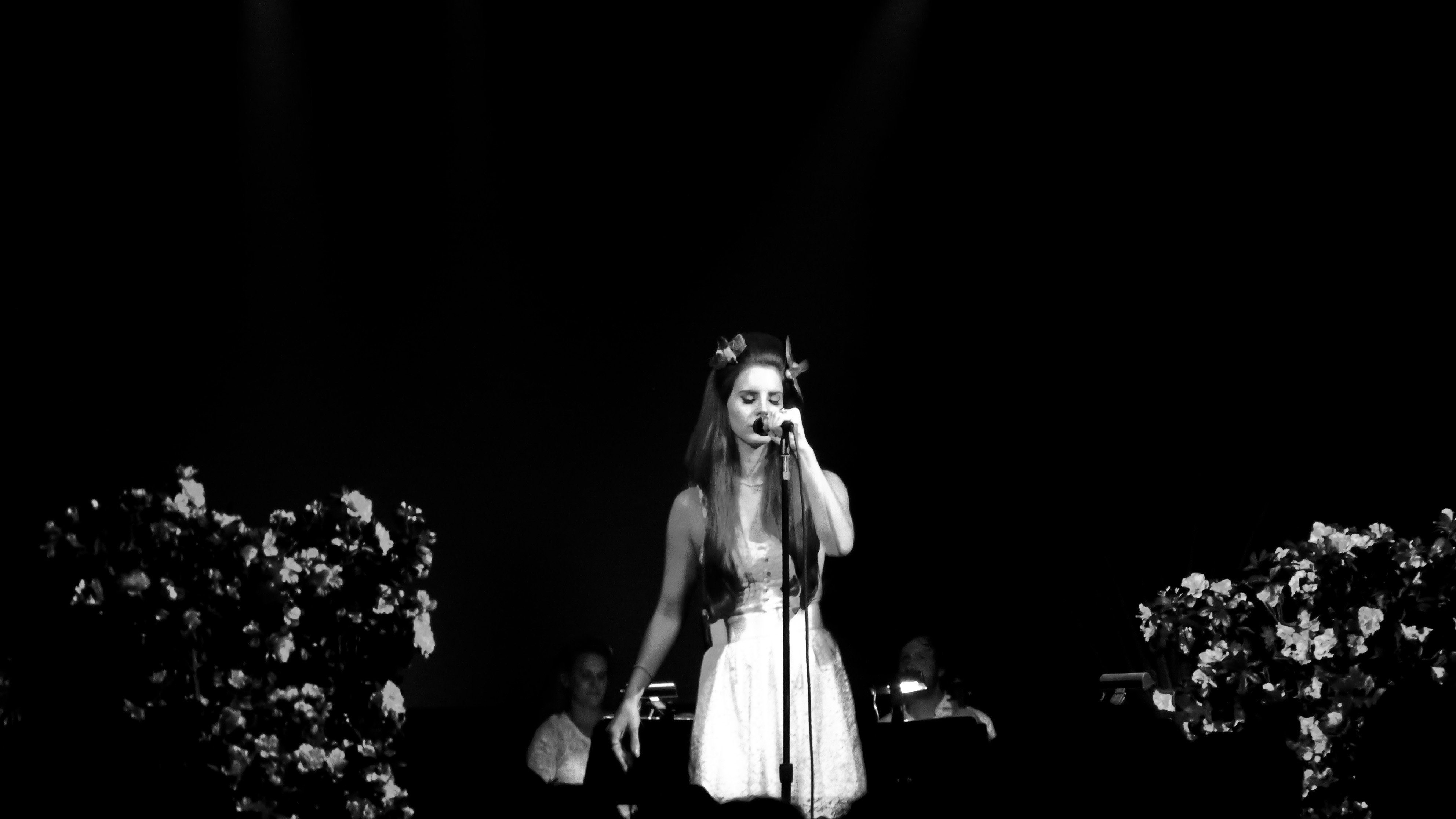 A woman in white dress singing on stage - Lana Del Rey