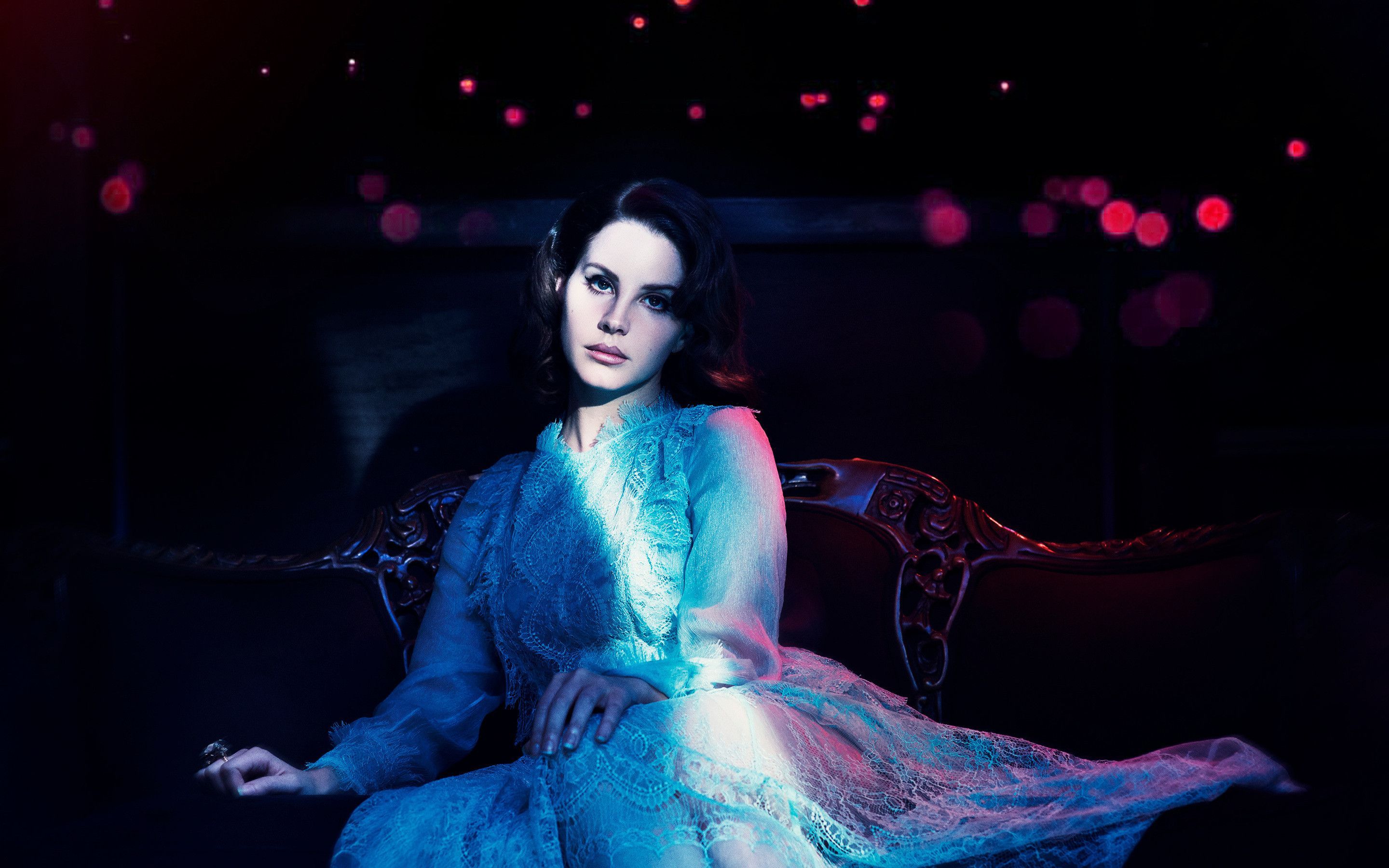 A woman in a blue dress sitting on a couch - Lana Del Rey