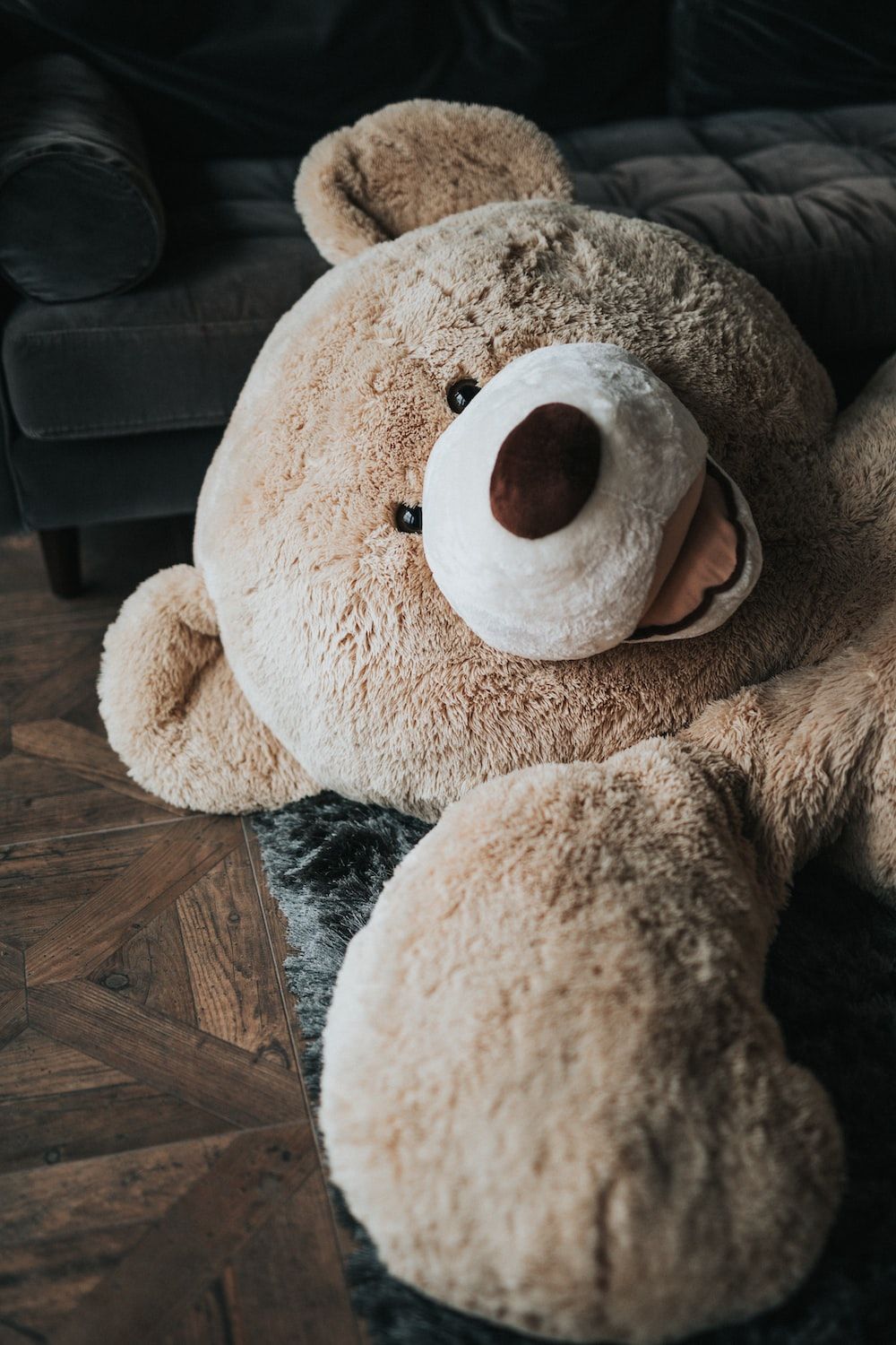 A large brown teddy bear sitting on a couch - Teddy bear