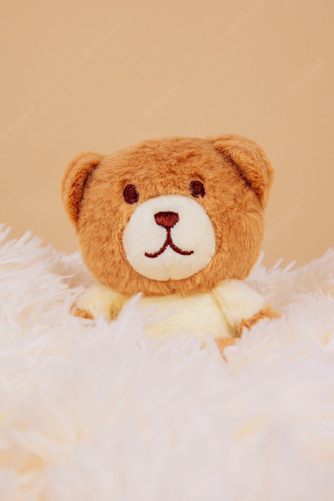 A brown teddy bear sitting on a white fluffy blanket - Teddy bear