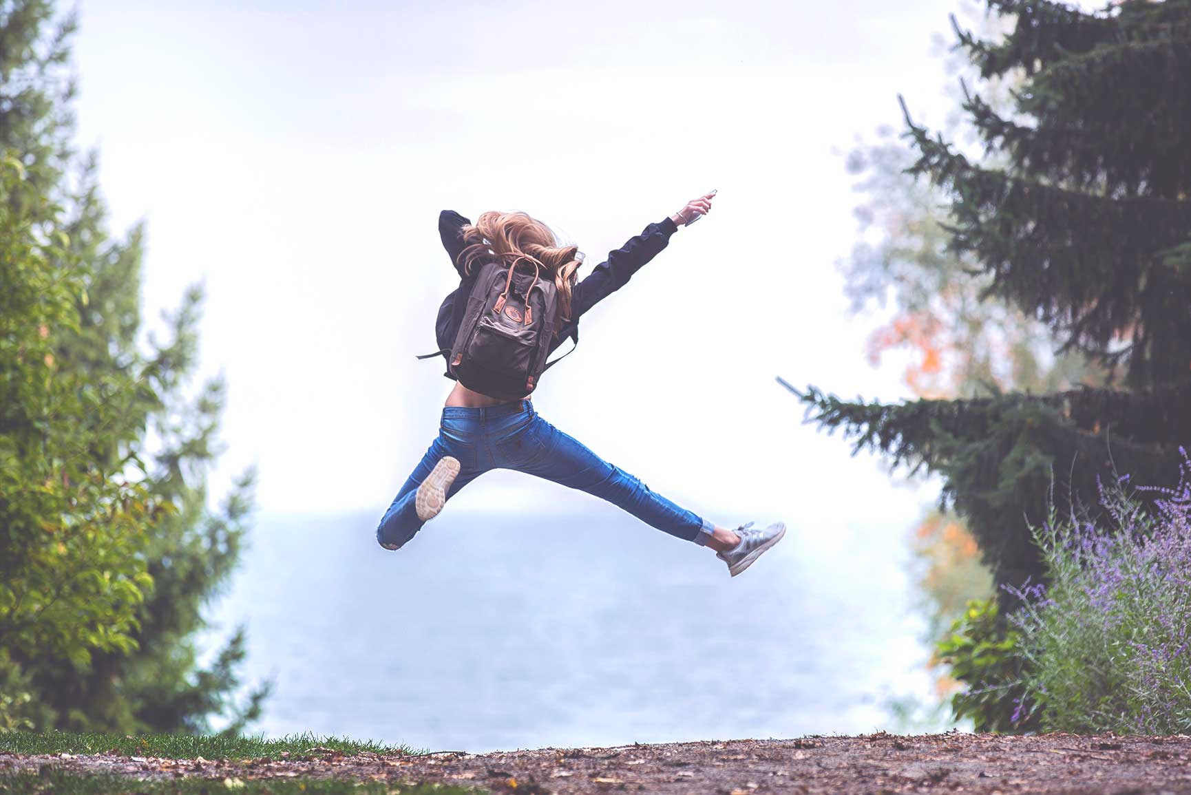 A woman jumping in the air on top of some rocks - Preppy