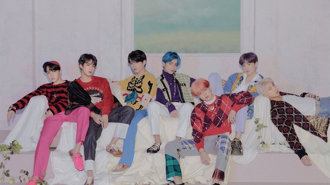 BTS sitting on a white couch in a pink room - BTS