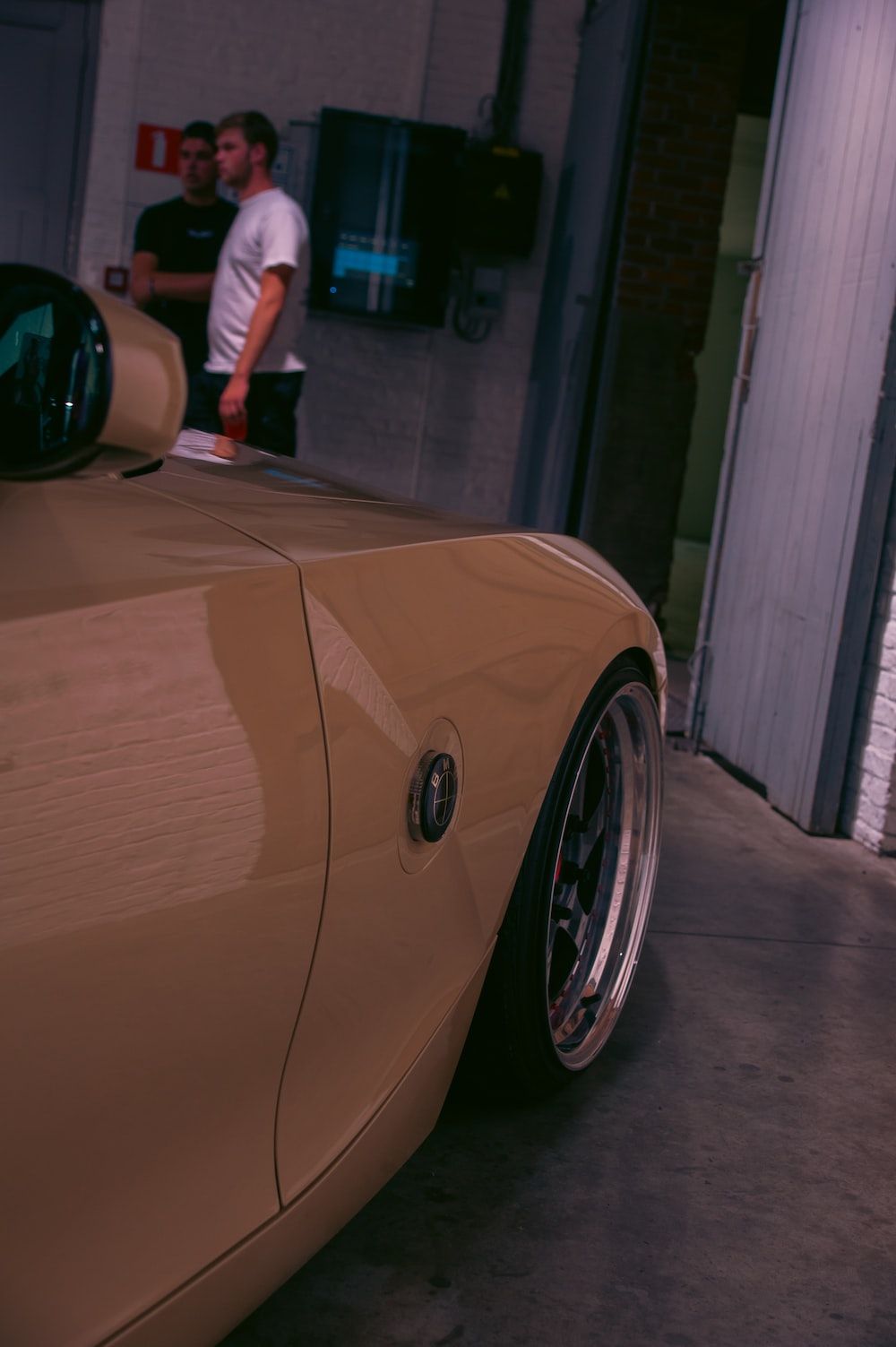 A tan sports car is parked in a garage. - JDM
