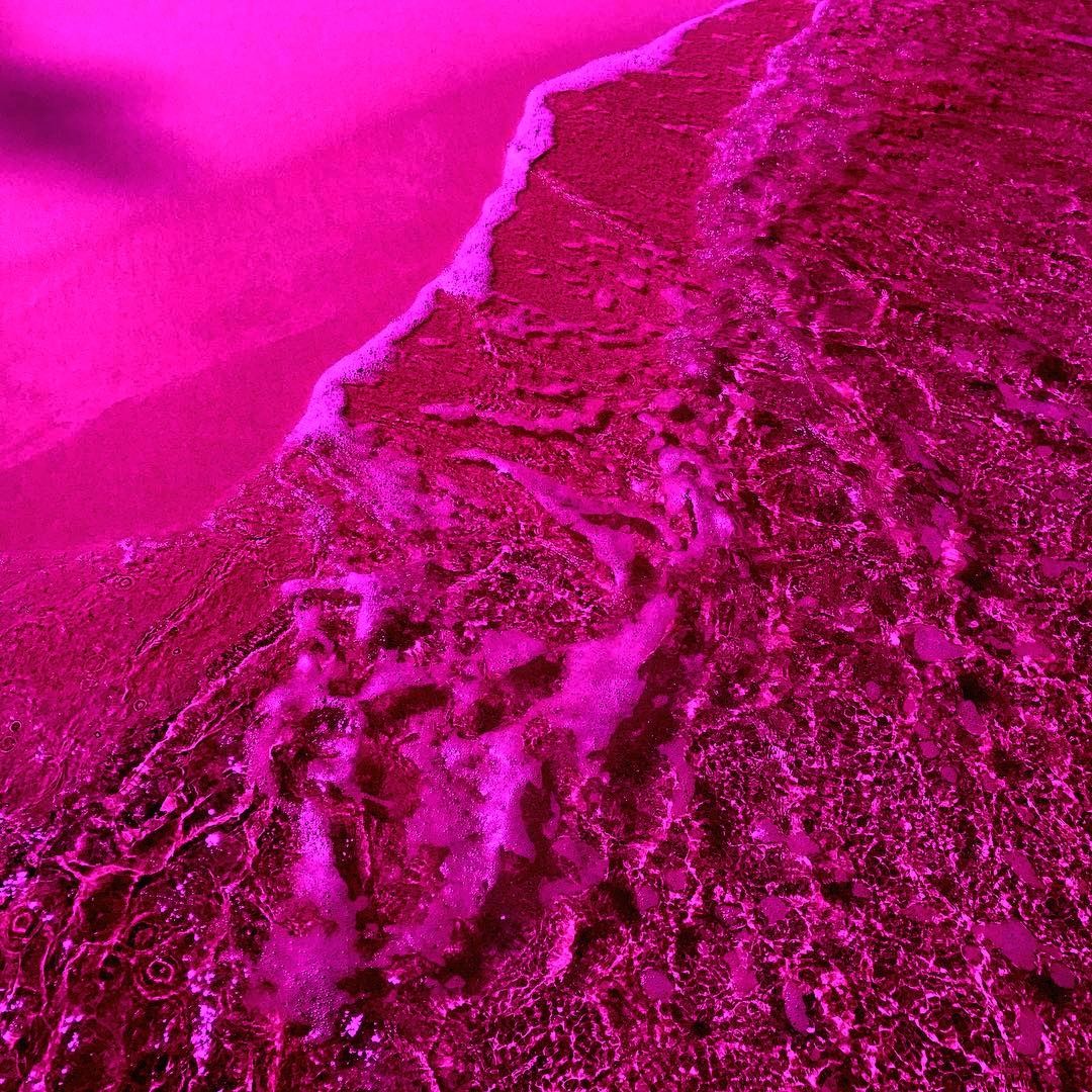 A close up of a wave hitting the shore - Hot pink, magenta