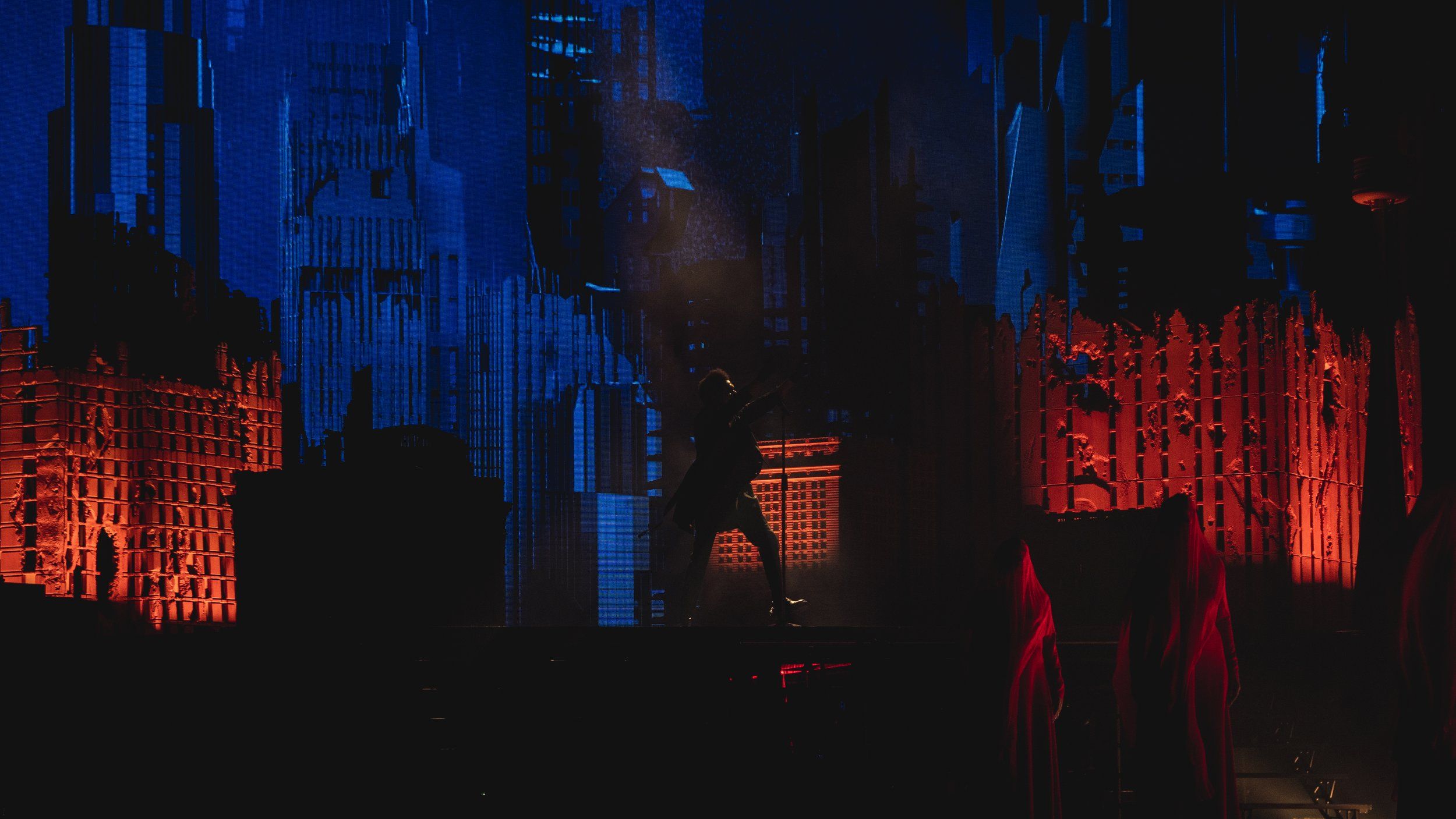 A man standing in front of a projection of a cityscape - The Weeknd