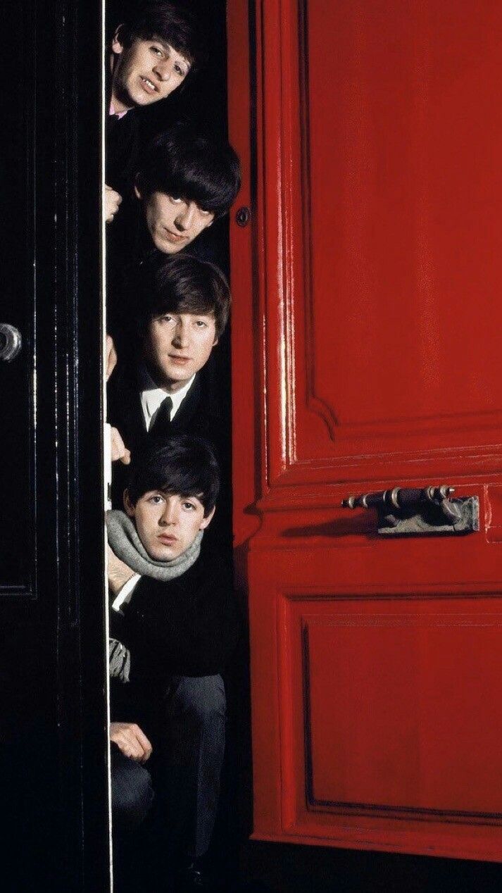 The Beatles peering around a red door. - 60s