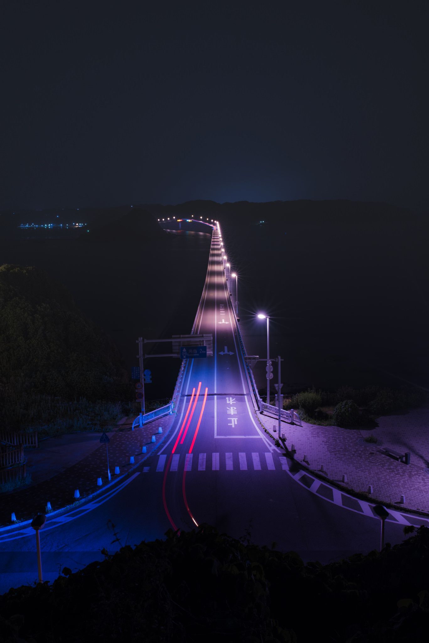 A long bridge with lights on it at night - 80s