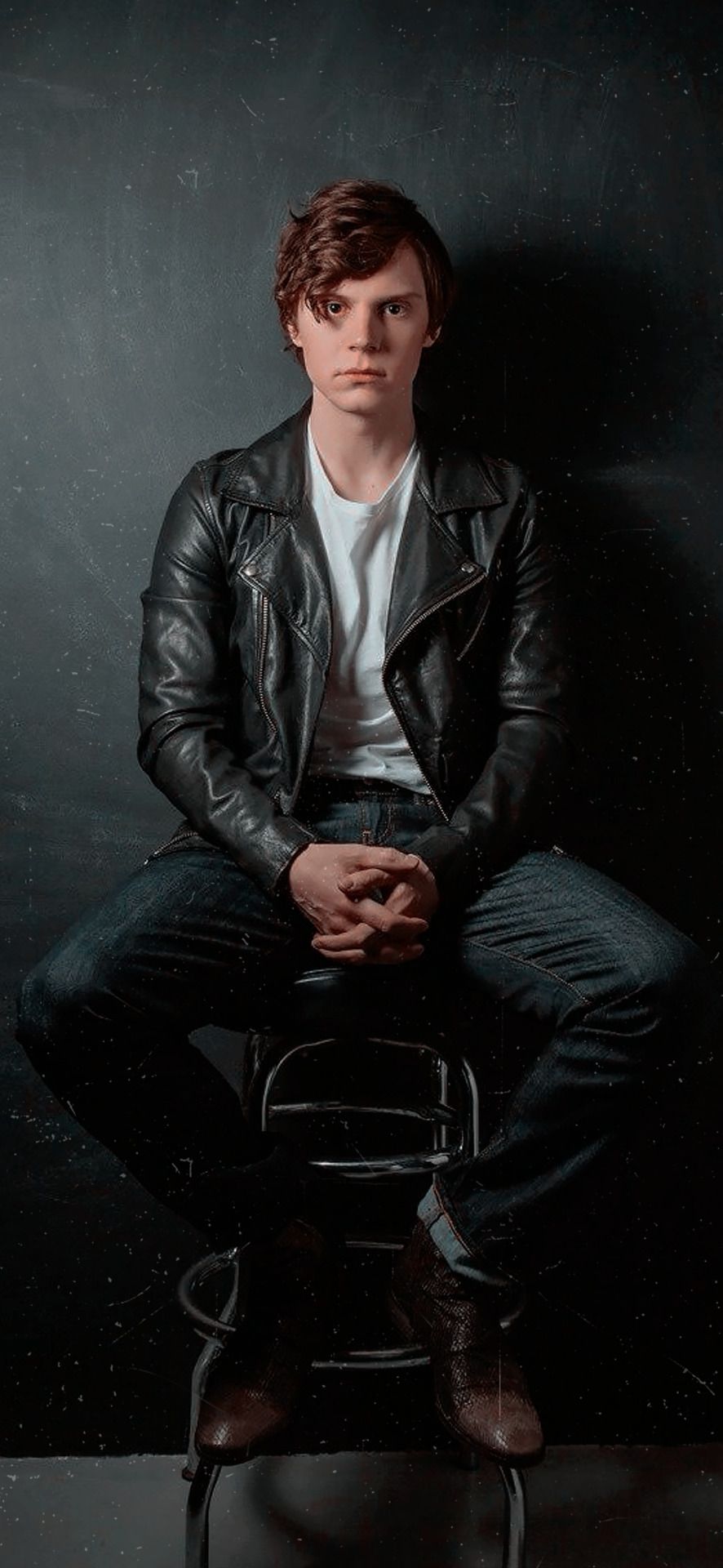 Evan Peters sitting on a stool in a leather jacket - Evan Peters