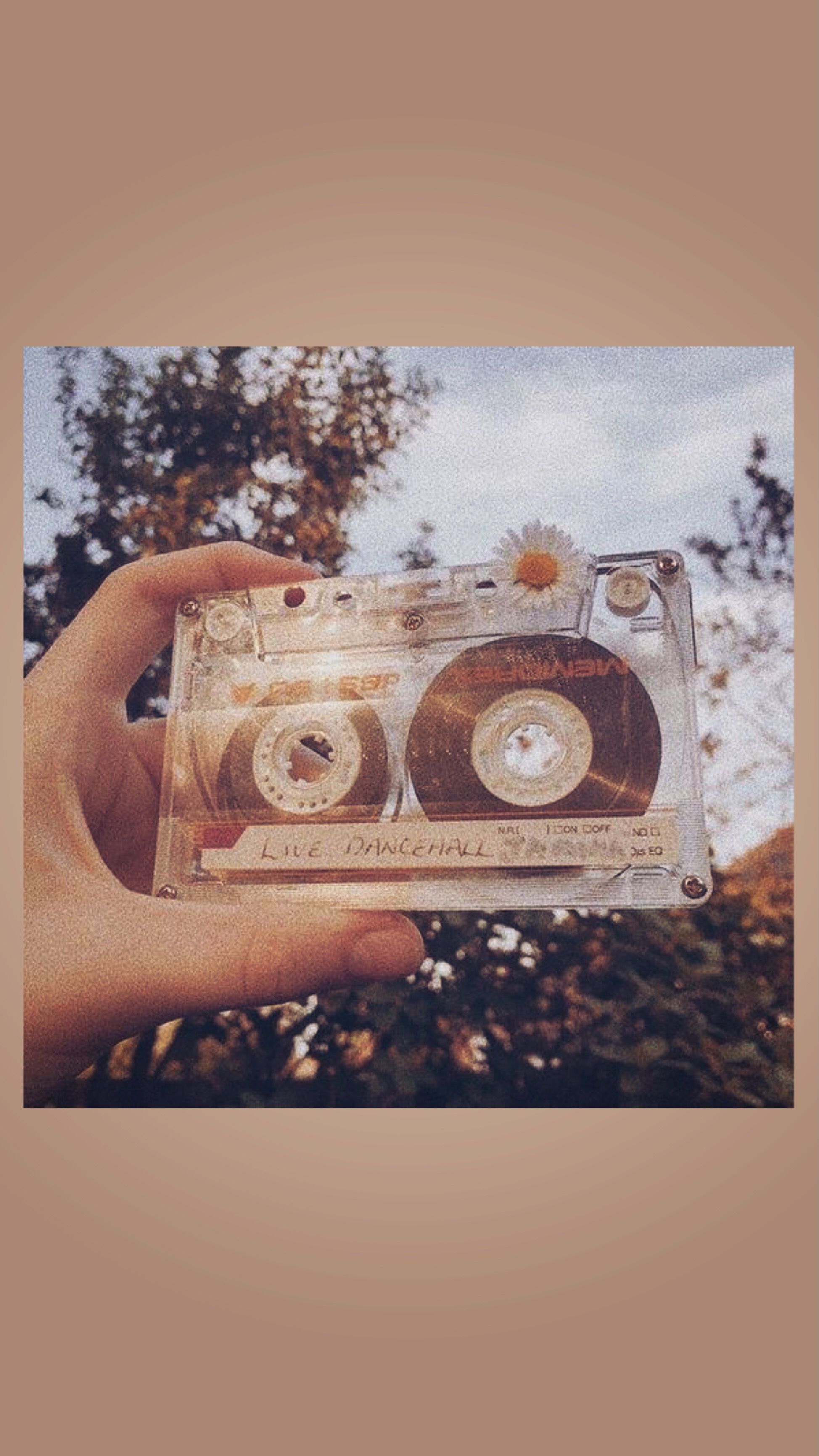 A person holding a cassette tape with a flower on it - Vintage