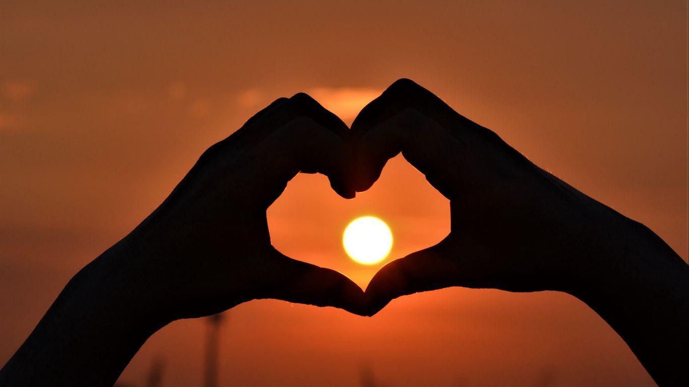 Silhouette of hands making a heart shape during sunset with a love theme. - Sun