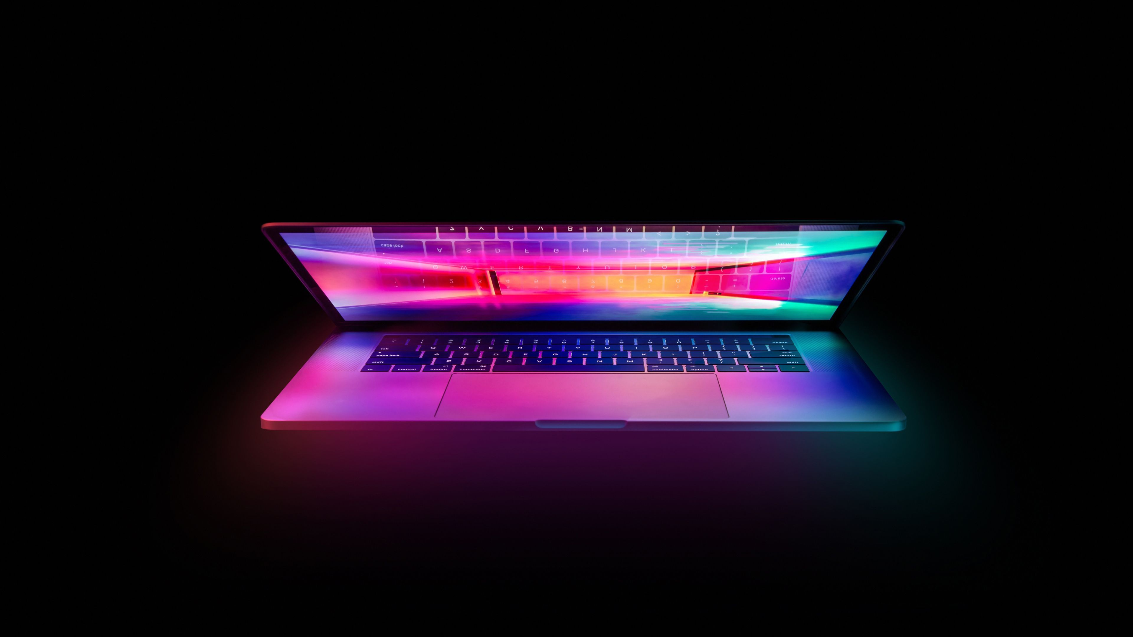 A laptop with a colorful display in a dark room - Laptop